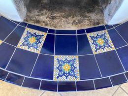 A blue and yellow tile floor with a fireplace in the background