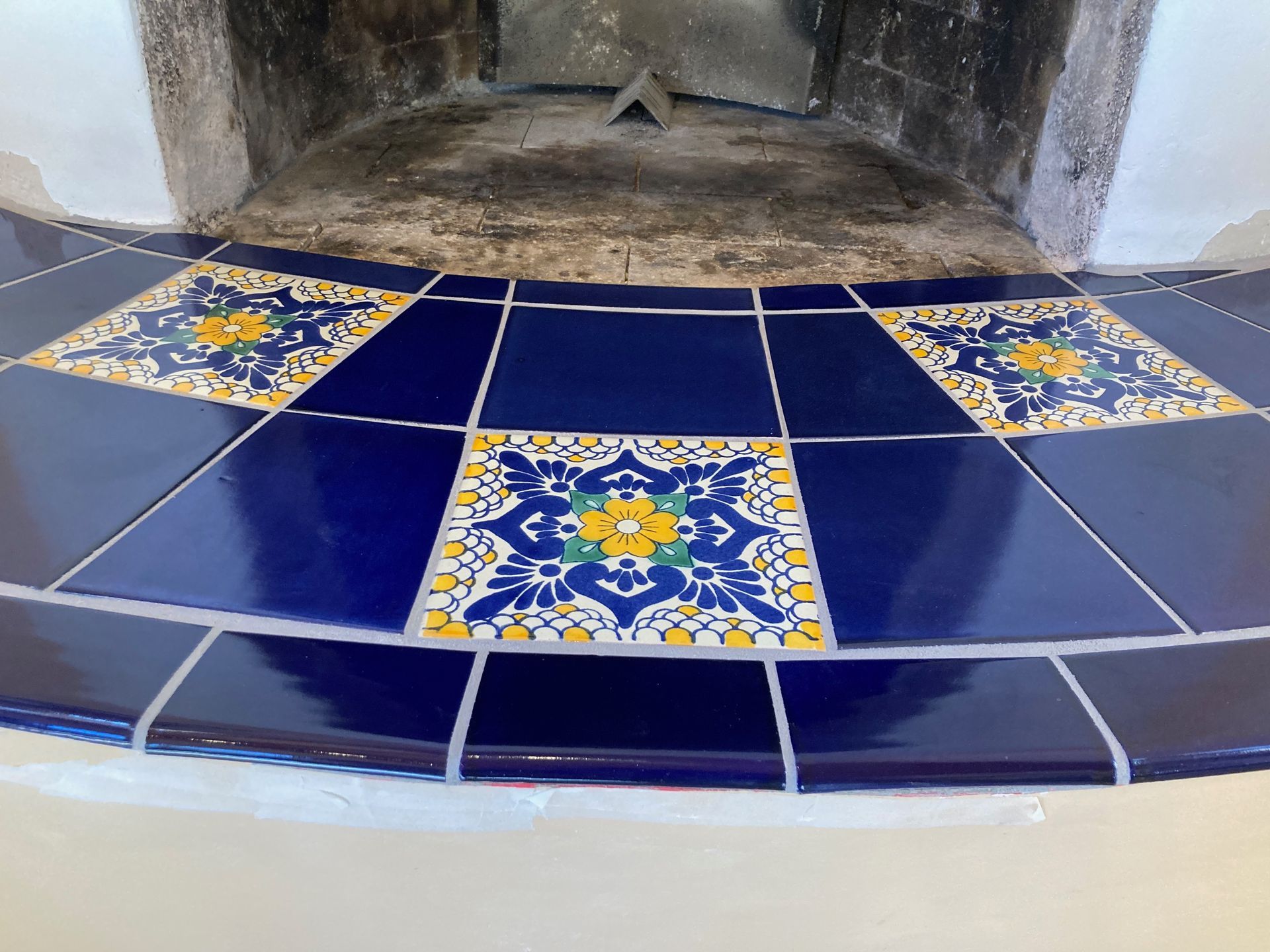 A blue and yellow tile floor with a fireplace in the background