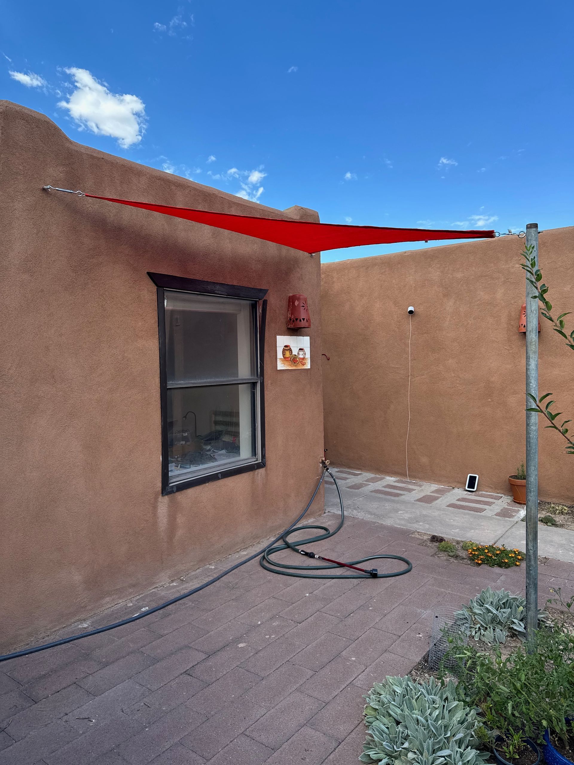 A red umbrella is hanging from the side of a house
