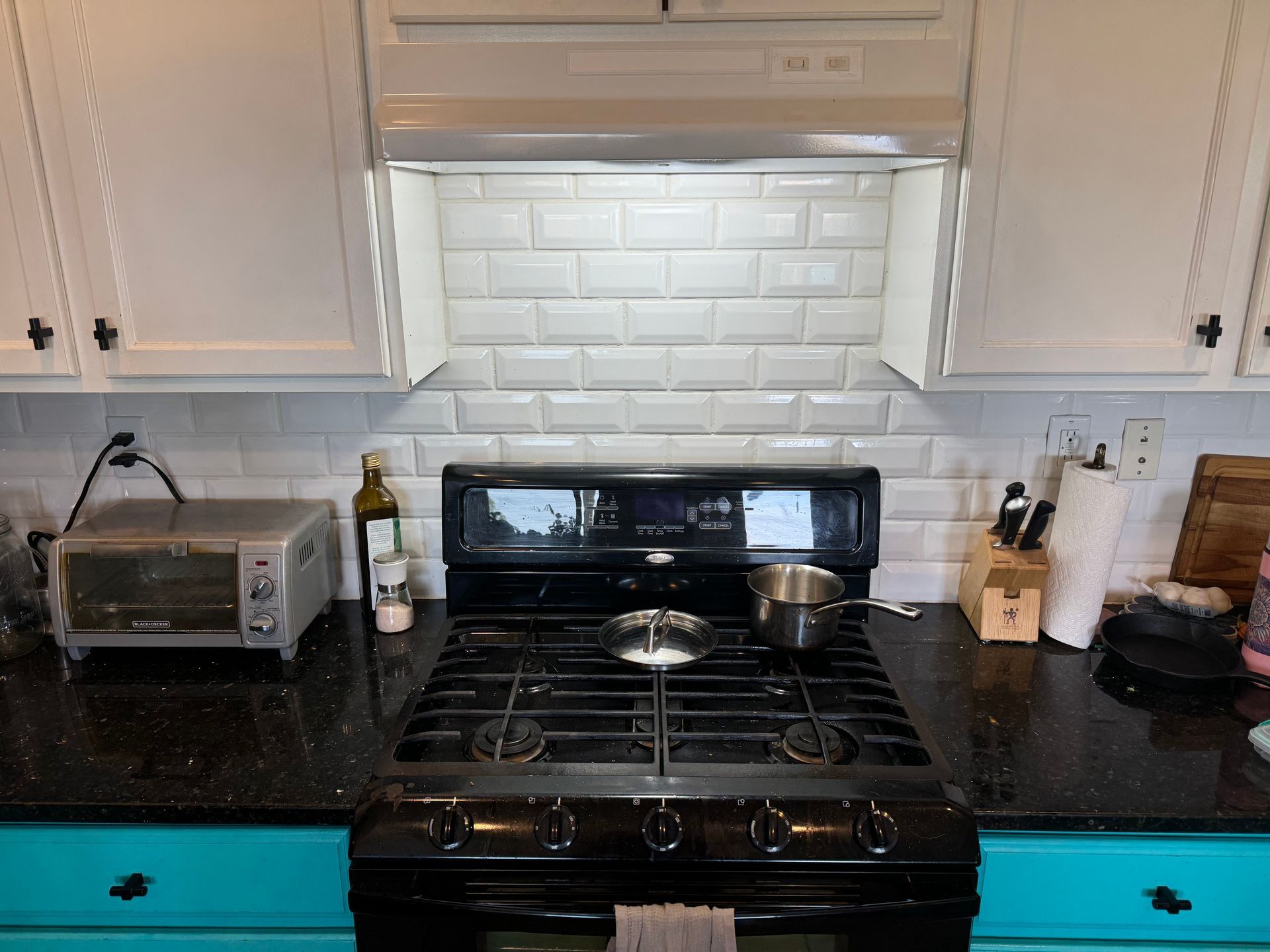 A kitchen with a black stove top oven and white cabinets