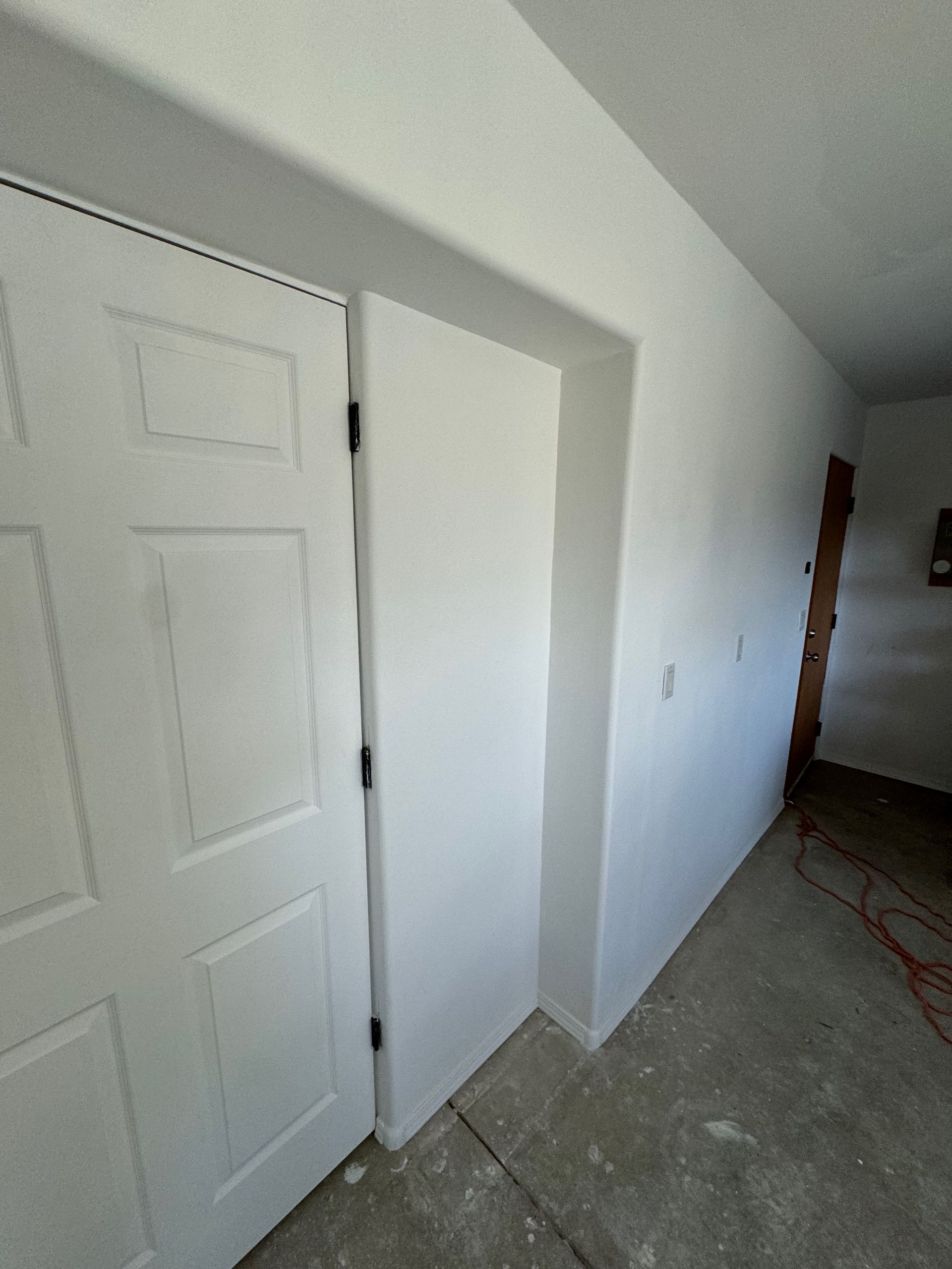 A hallway with two white doors and a wooden door.