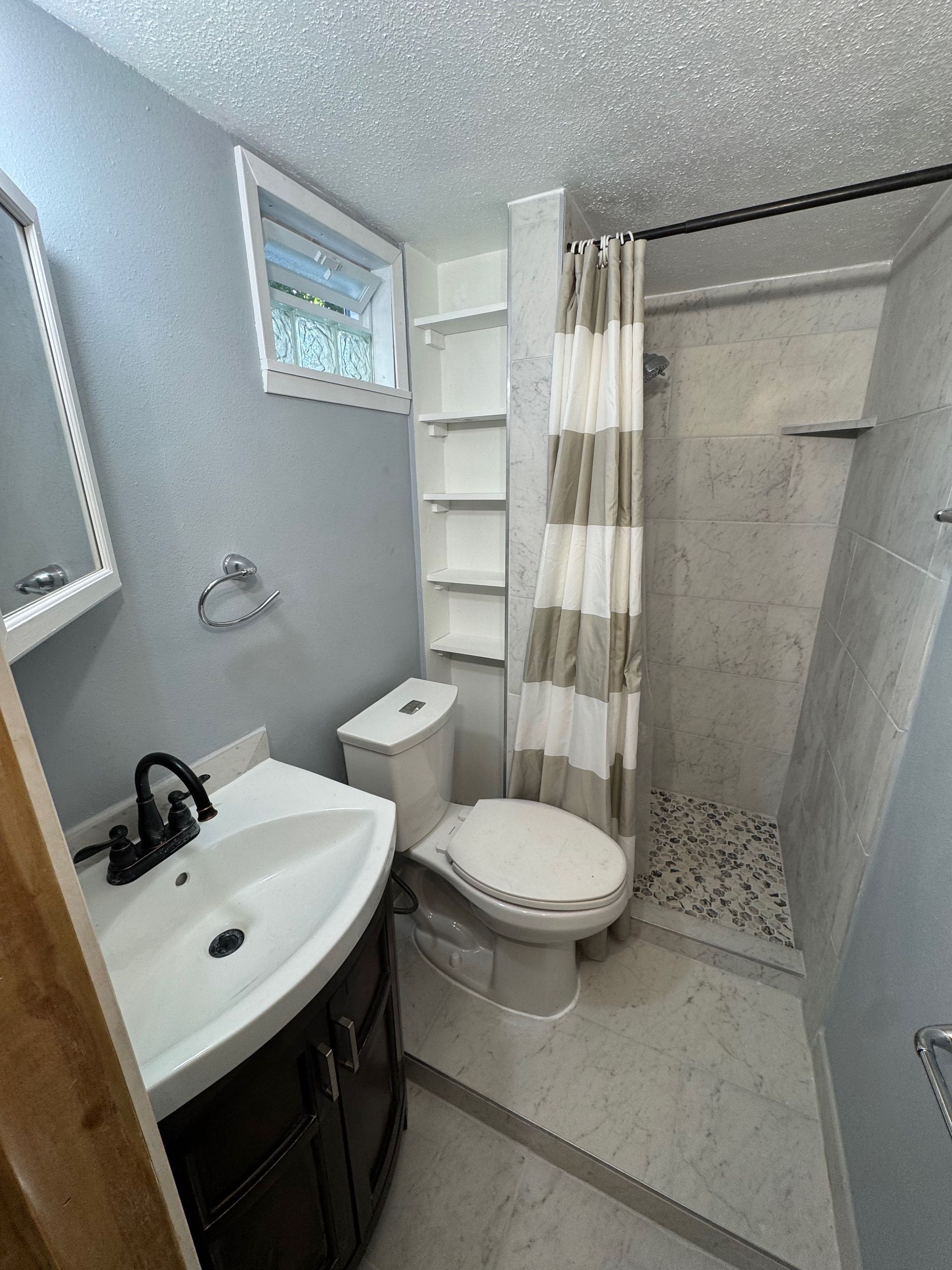 A bathroom with a toilet , sink and shower.