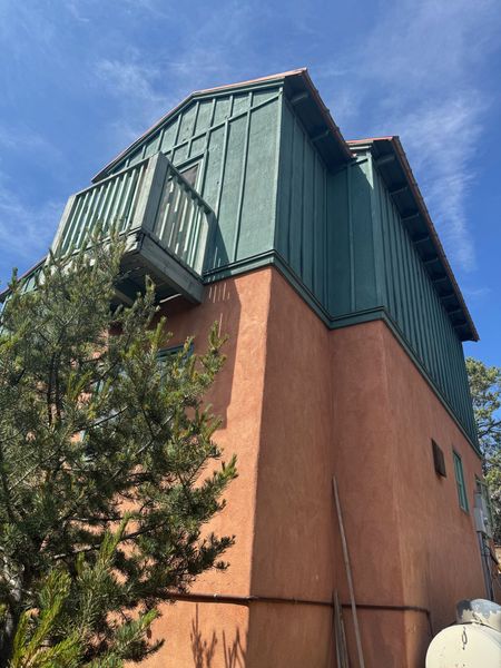 The side of a building with a green roof and a balcony.