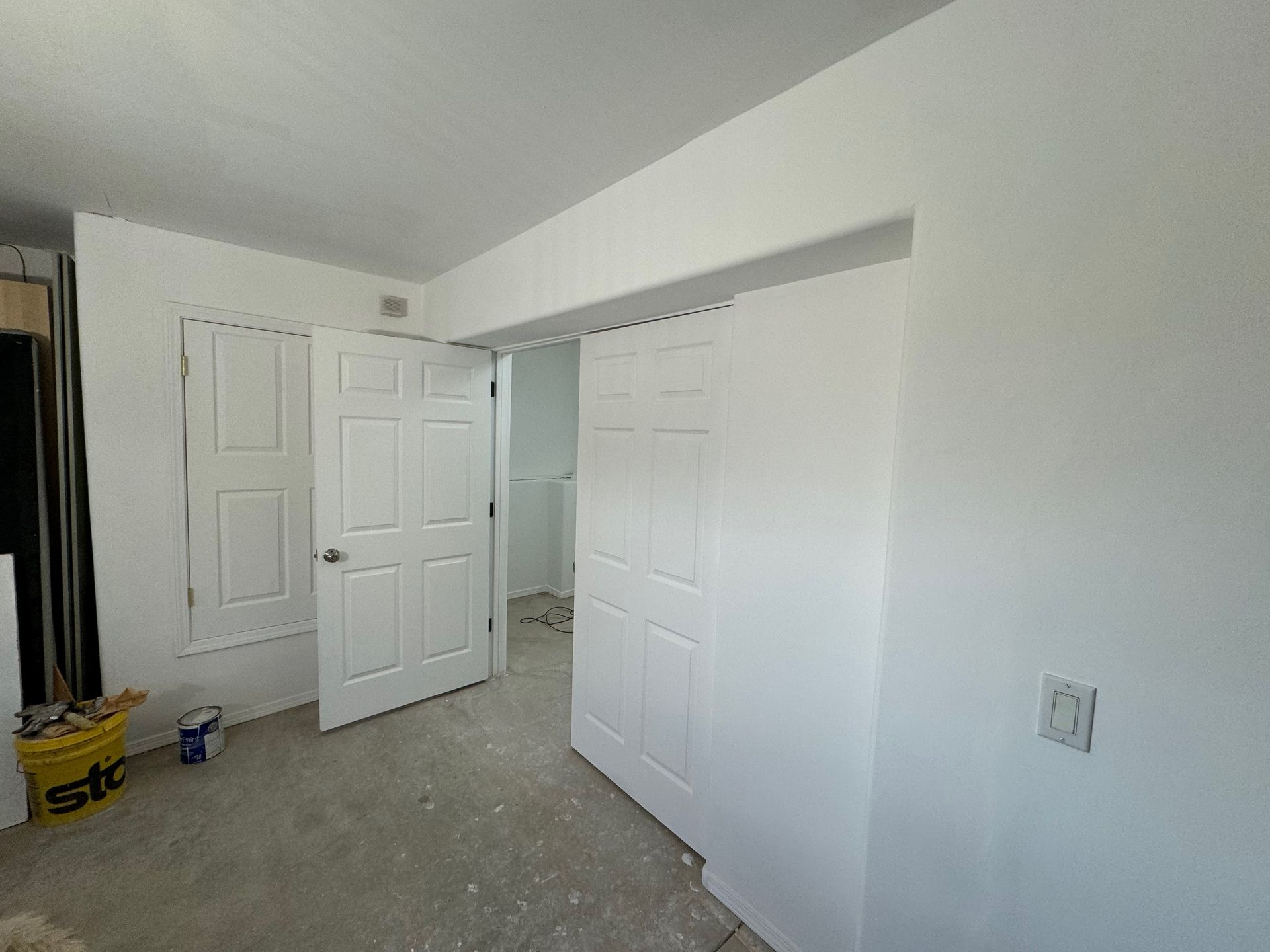 A bedroom with white walls and sliding doors.