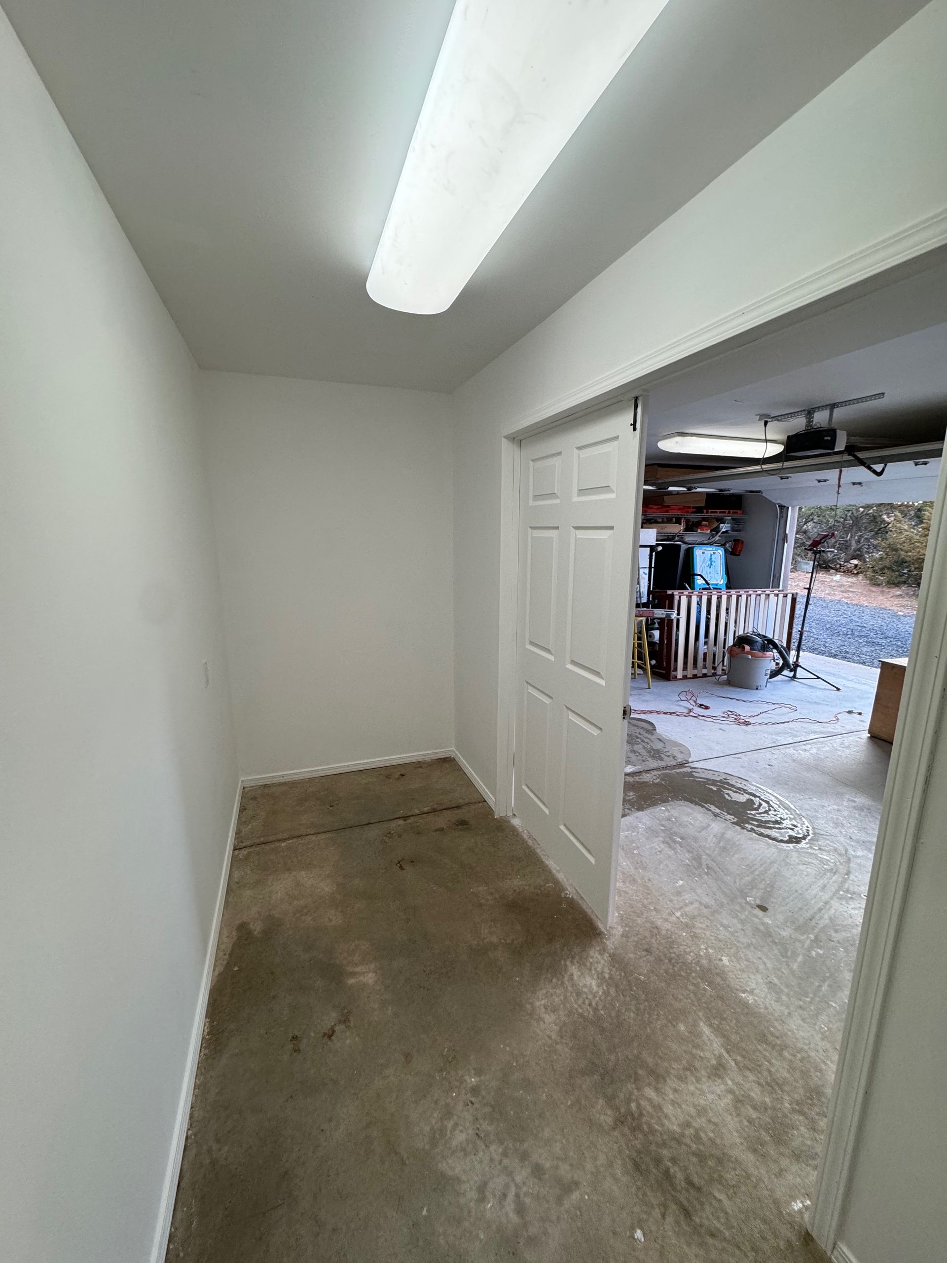 A room with a door that is open to a garage.