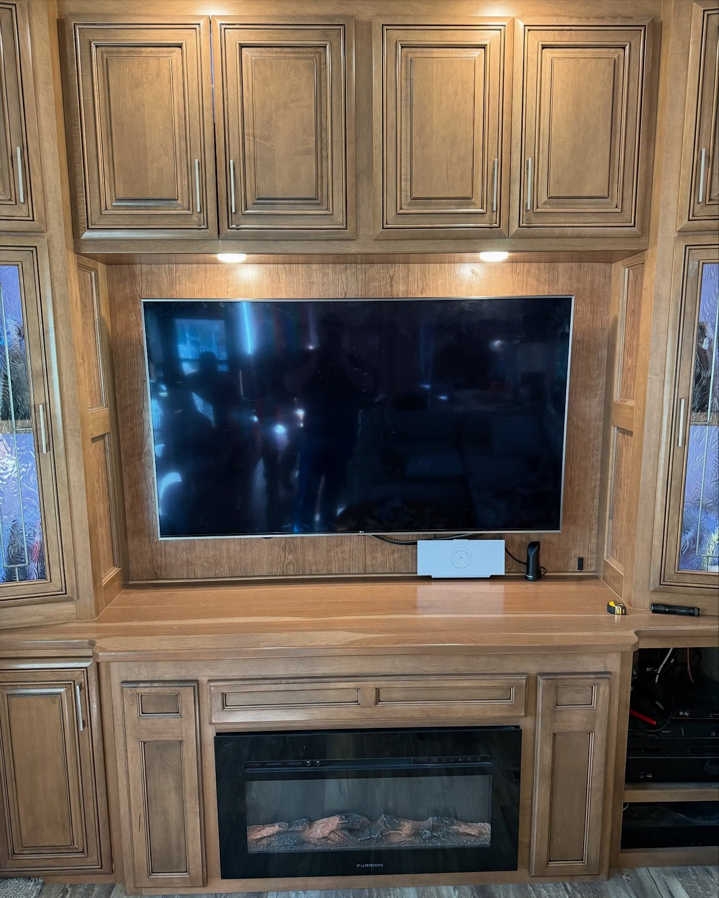 Wooden entertainment center with TV, fireplace, and cabinets.