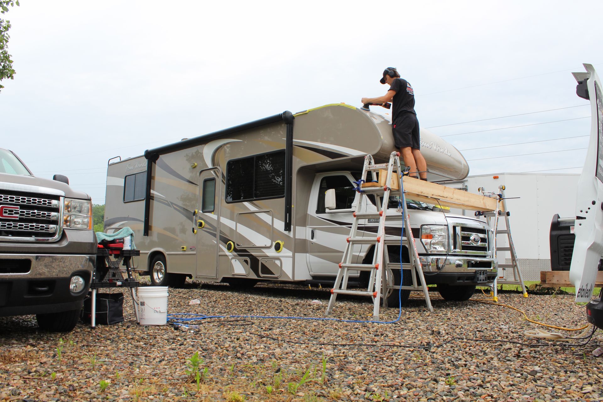 A white and black rv is parked in a driveway next to a house.