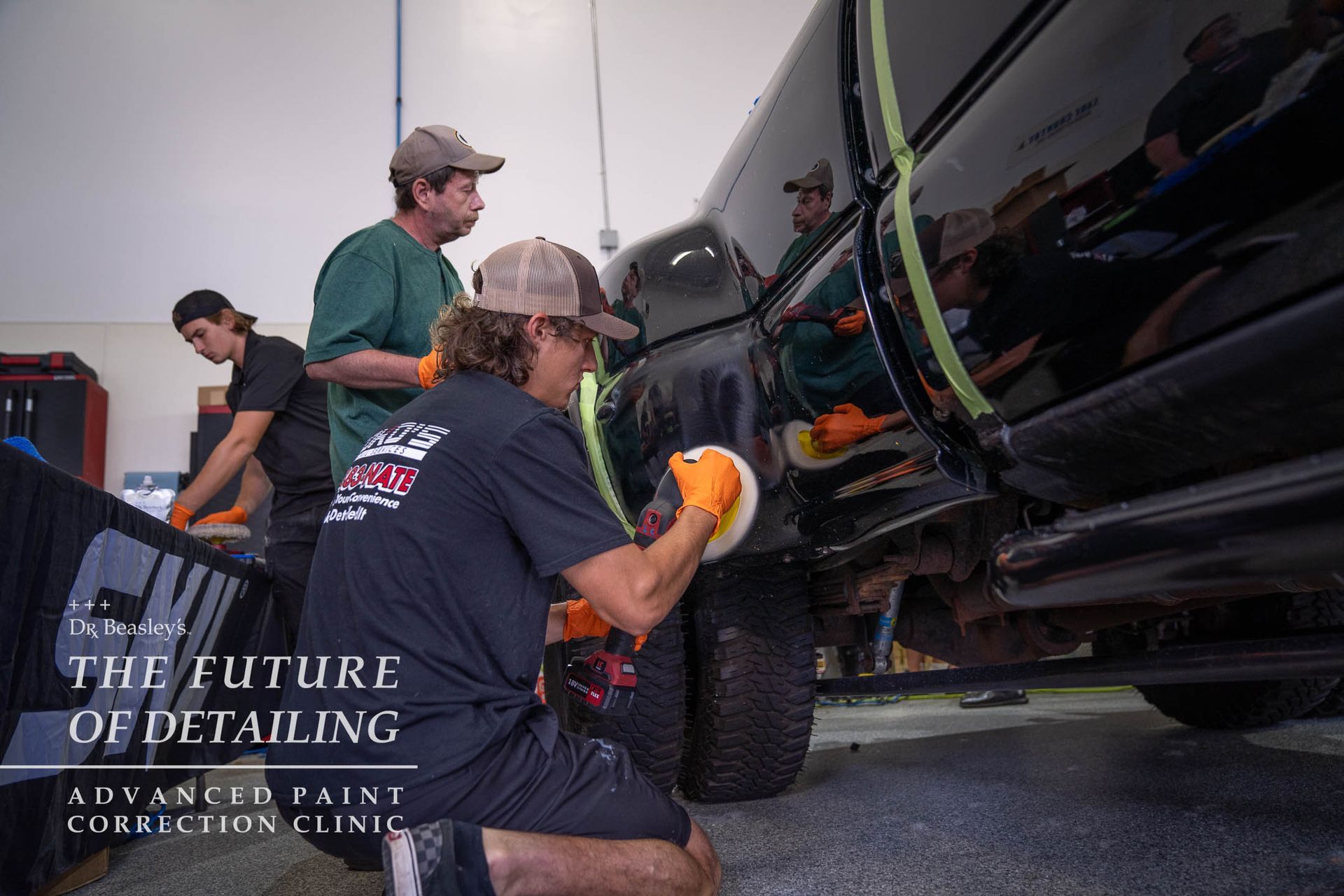 A group of men are polishing a truck in a garage.