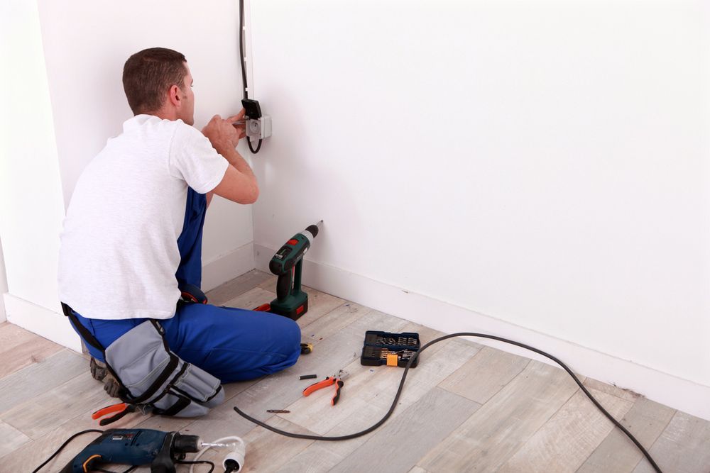 Electrician Installing An Outlet On A White Wall, Using Tools On The Floor— John B Electrical In Wooragee VIC