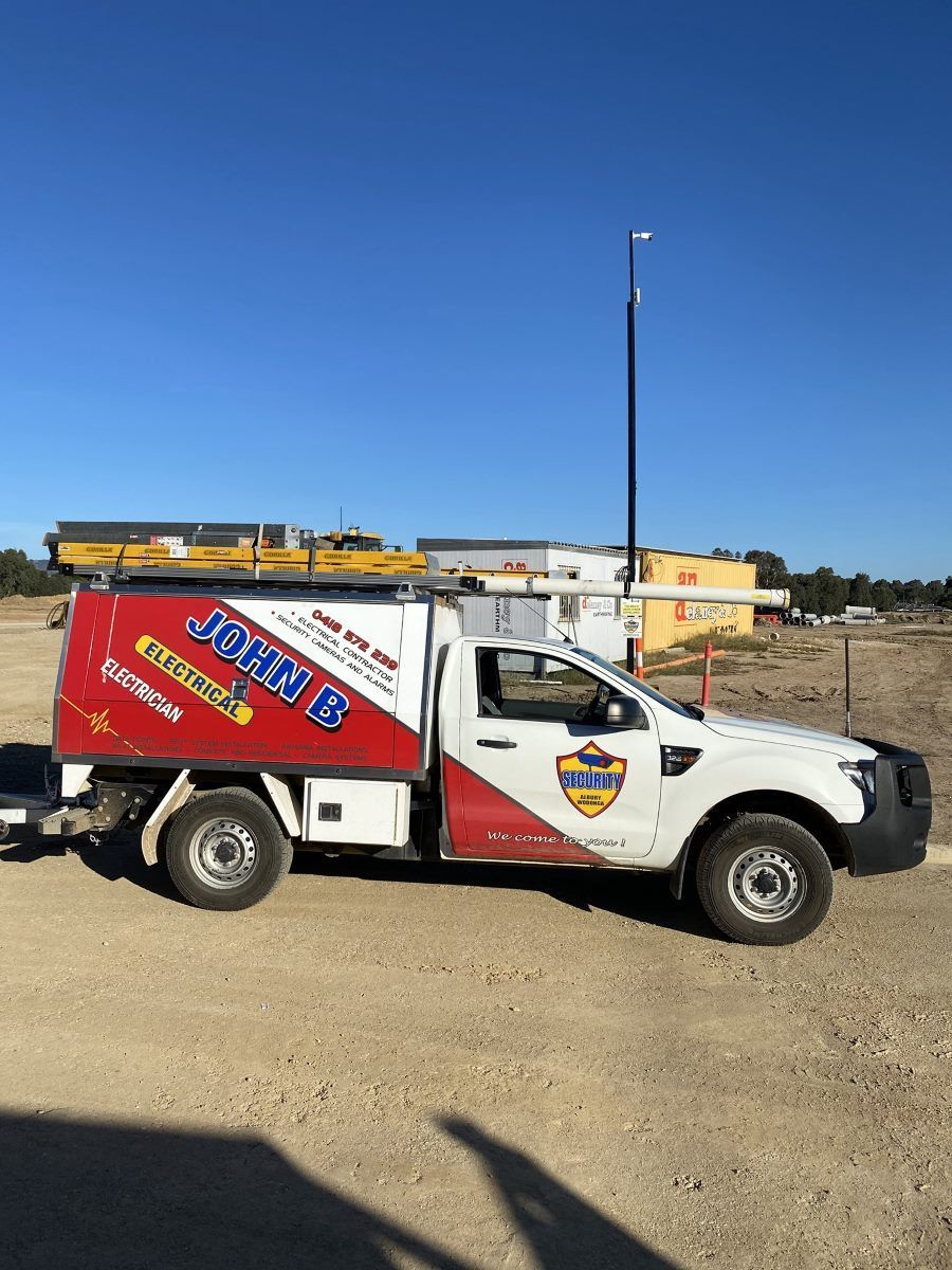 A White and Red Truck is Parked in a Dirt Field — John B Electrical In Albury NSW