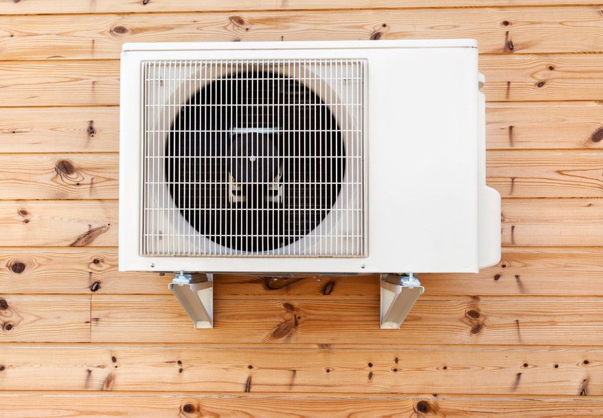 Airconditioning Outdoor Unit On A Wooden Background — John B Electrical In Wodonga VIC