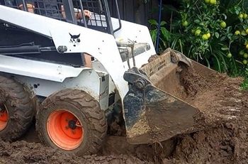 Bobcat Wollongong loader moving excavated materials to prepare for a driveway construction.