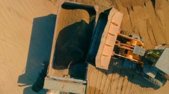 Top view of an excavator removing and dumping sand into a truck in a subdivision works in Wollongong NSW.