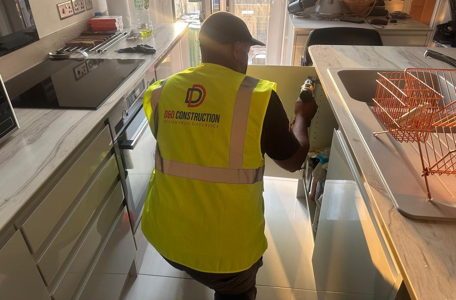 A man in a yellow safety vest is working in a kitchen for D&D Construction Nottingham, Derby