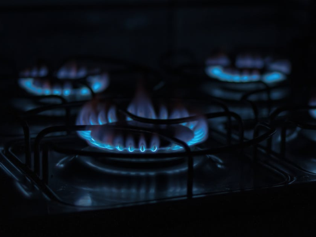 A close up of a gas stove with blue flames in the dark. D&D Construction Nottingham