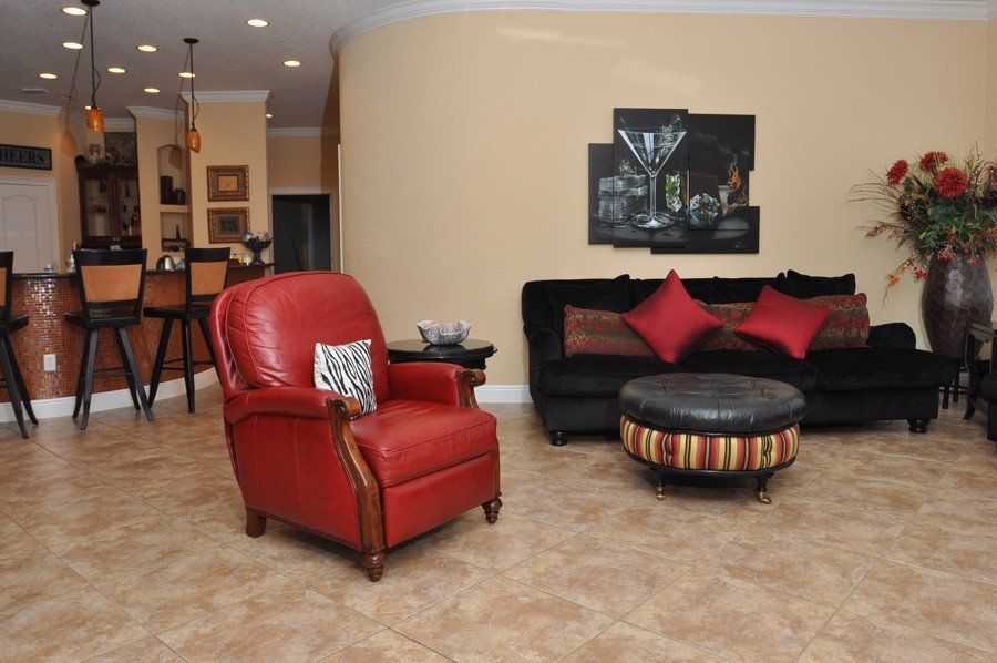 A living room with a red chair and a black couch