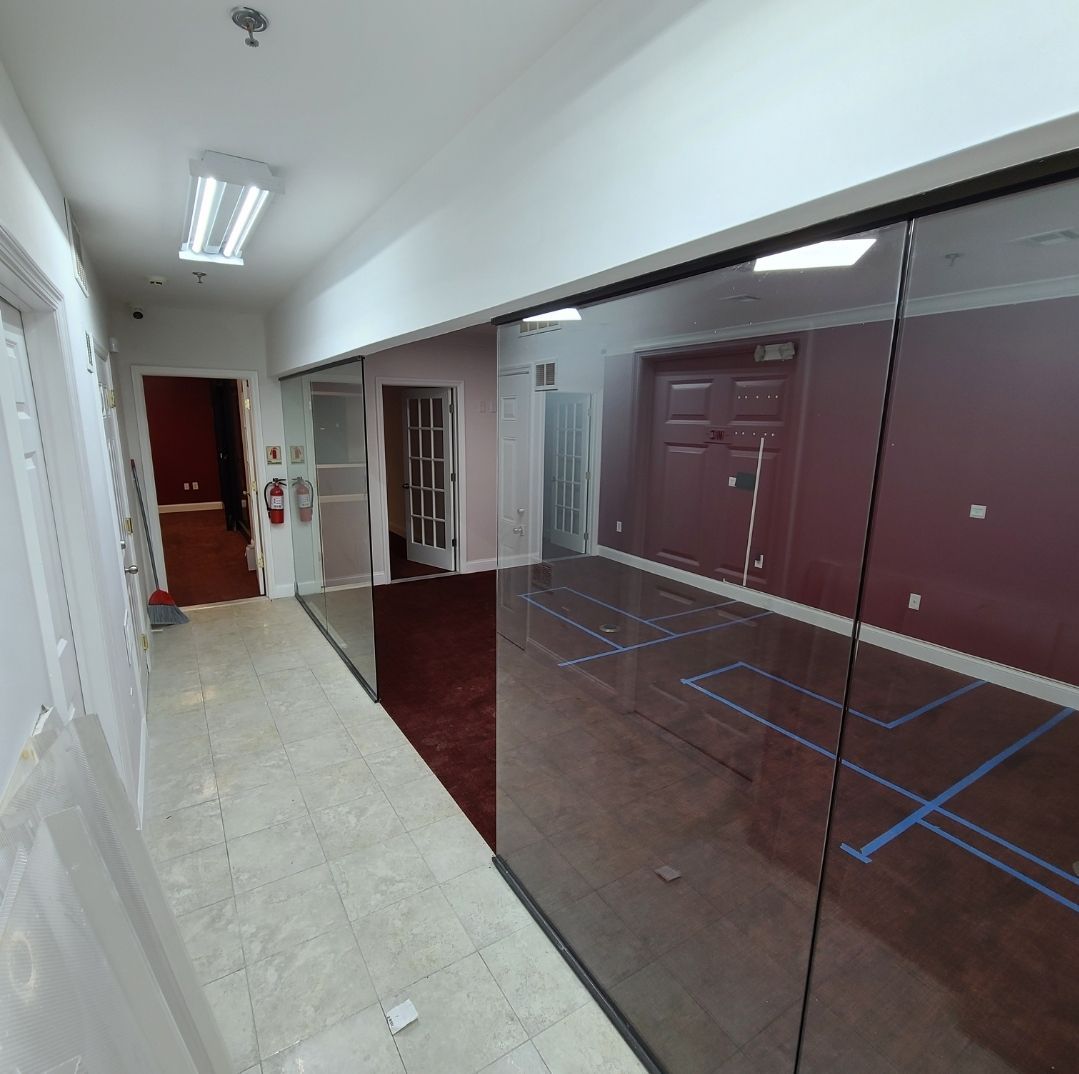 A long hallway with glass walls and a fire extinguisher on the wall