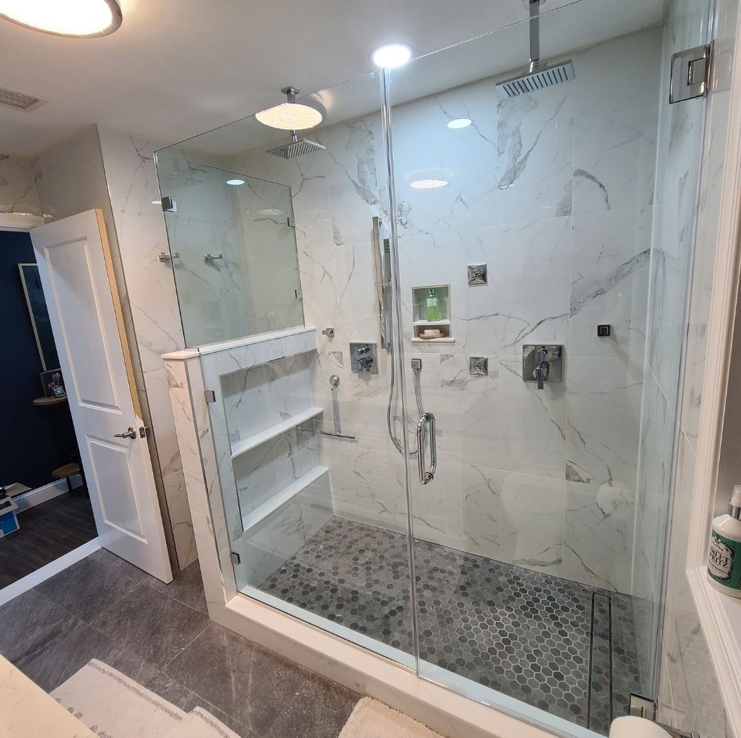 A bathroom with a walk in shower with a glass door.