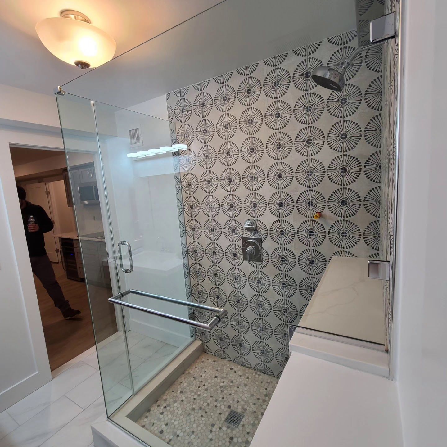 A bathroom with a walk in shower with a glass door