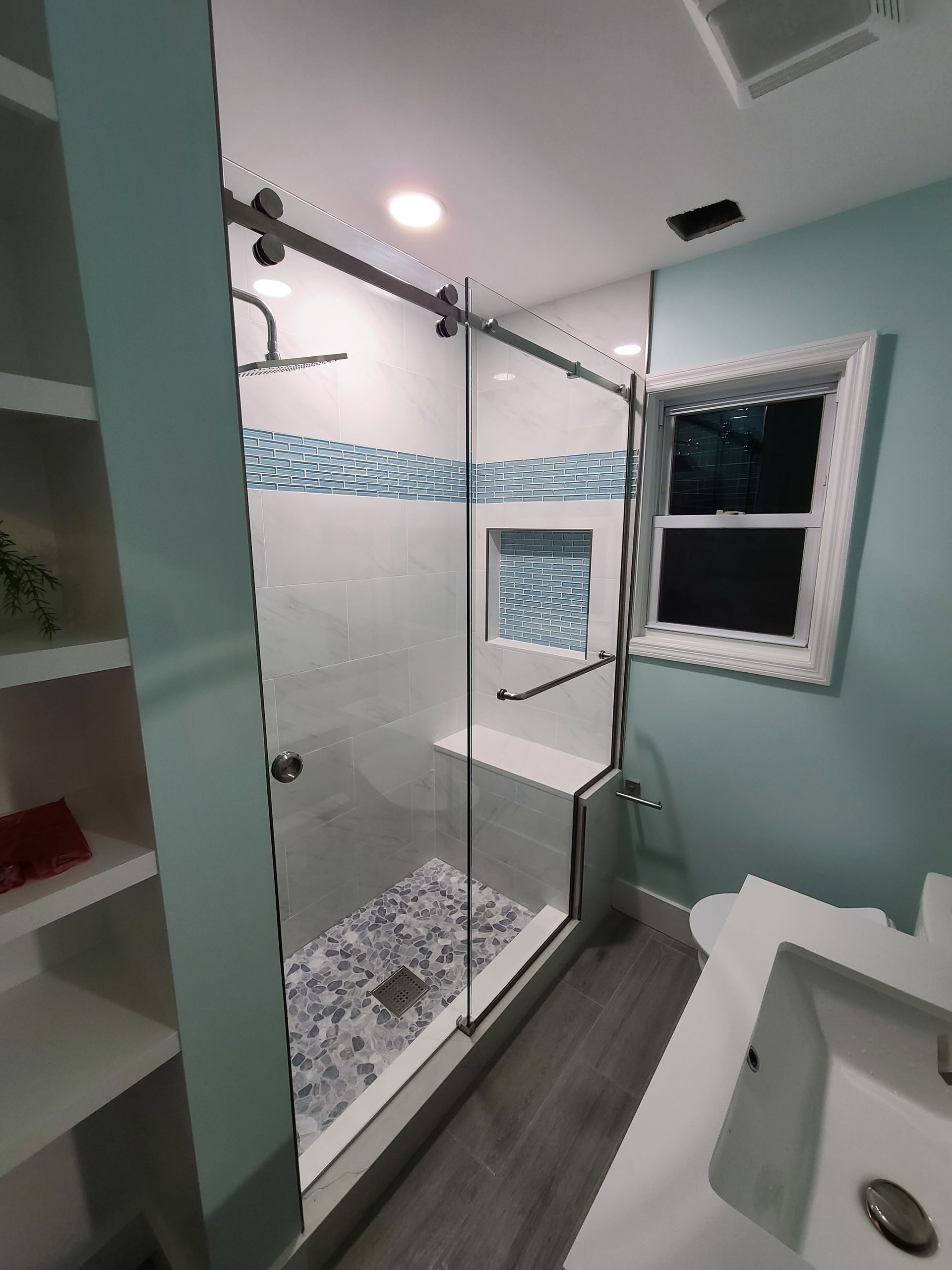 A bathroom with a walk in shower and a sink