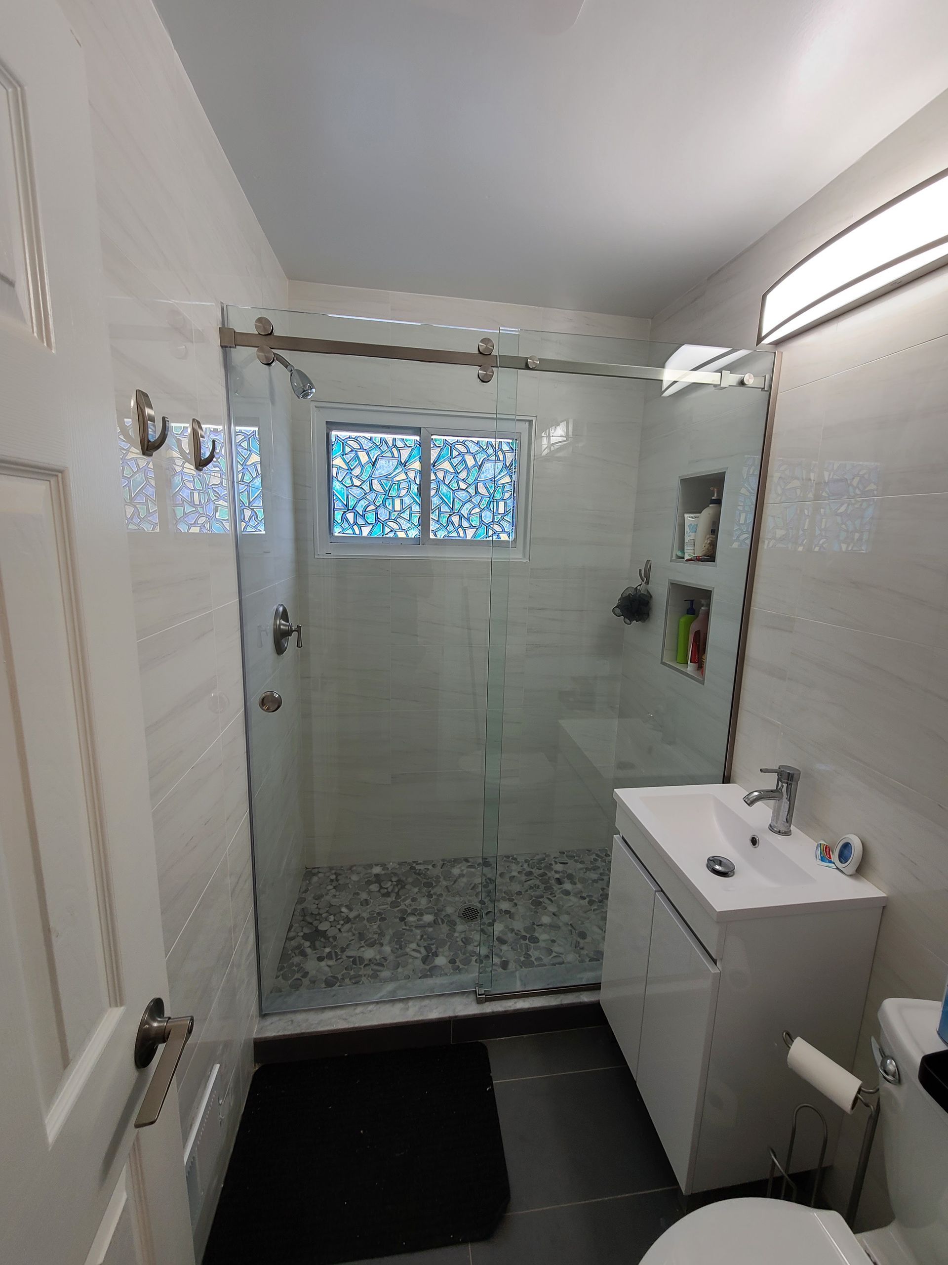 A bathroom with a toilet , sink , shower and window.