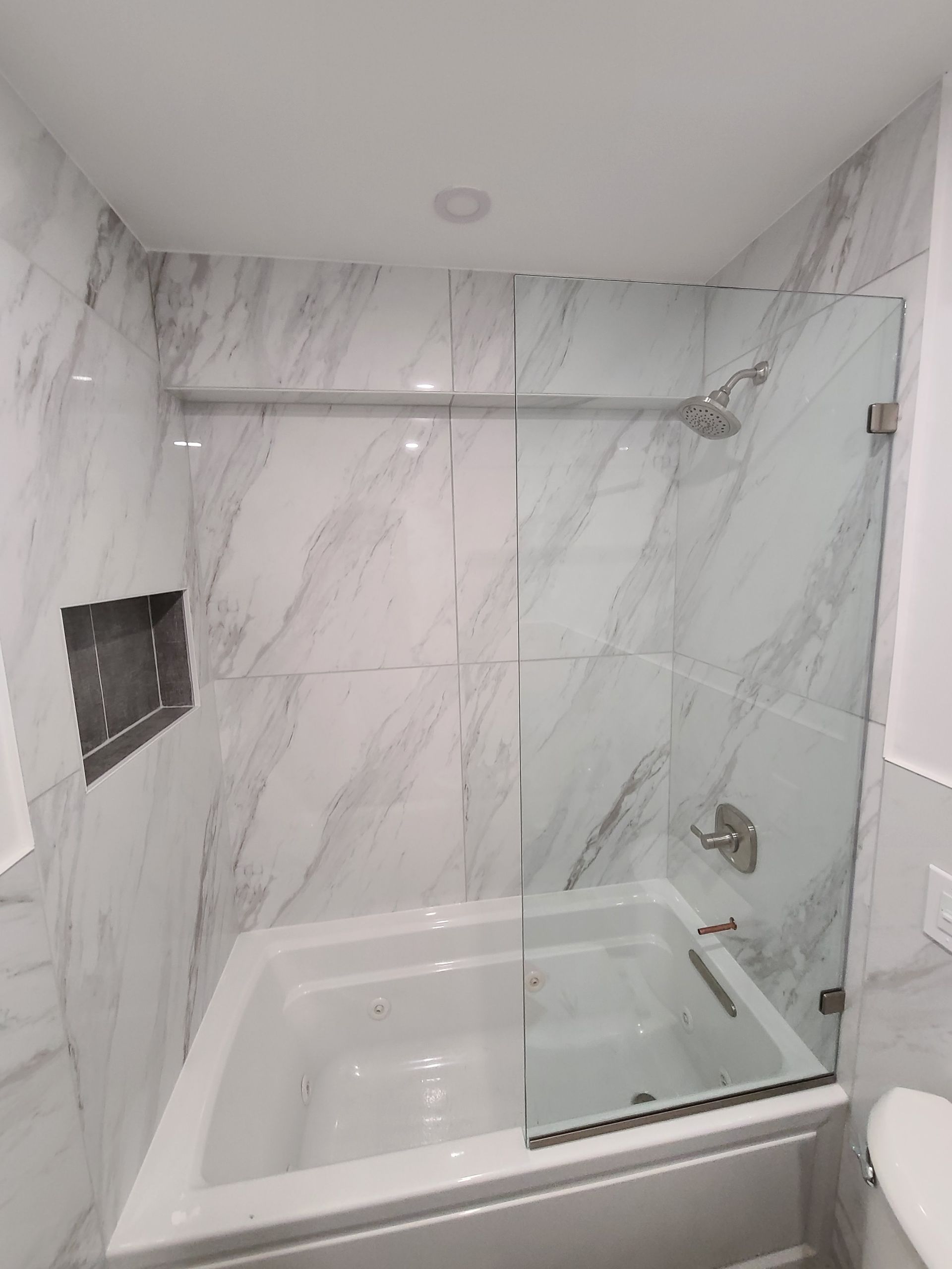 A bathroom with a tub and a shower with a glass door.