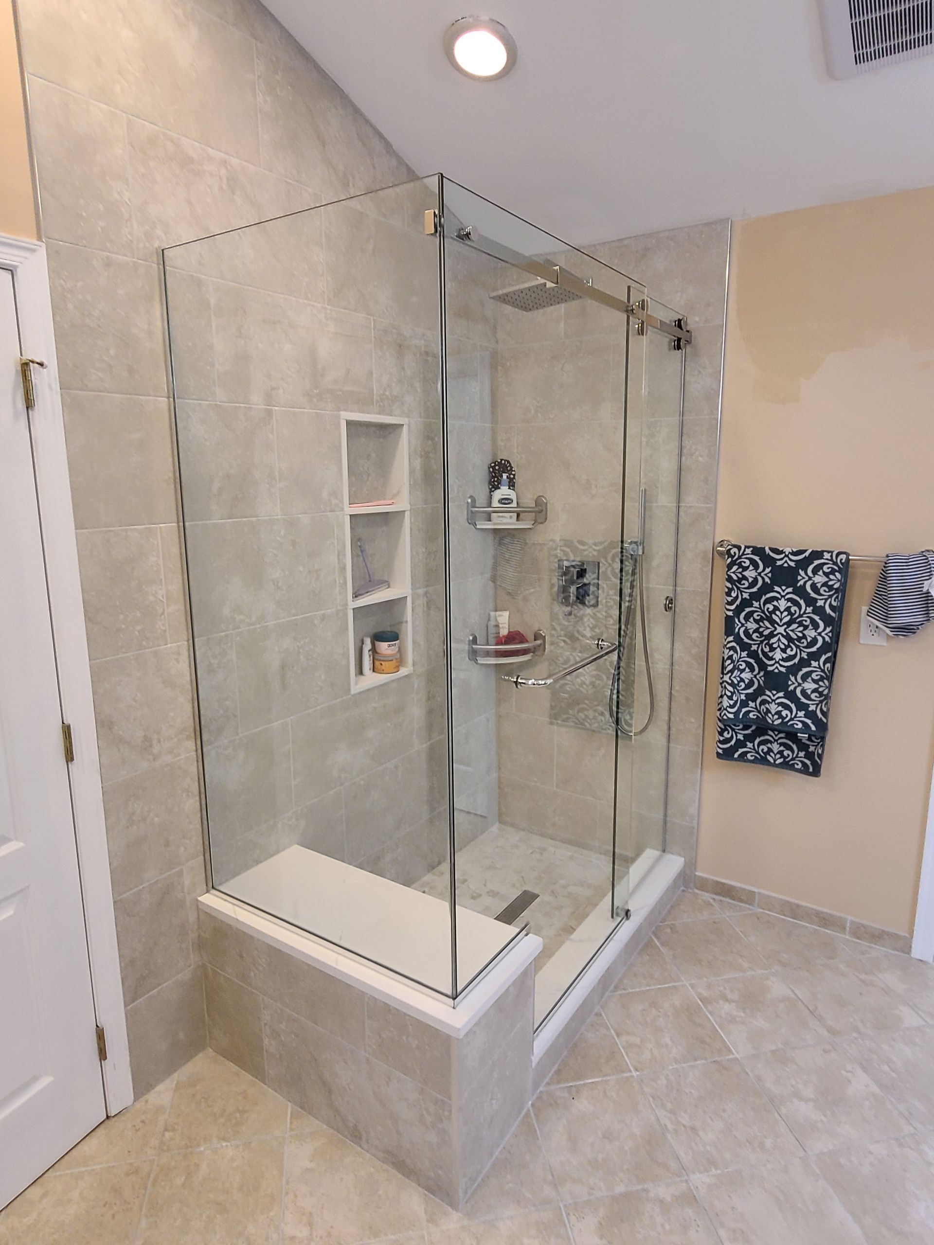 A bathroom with a walk in shower with a glass door