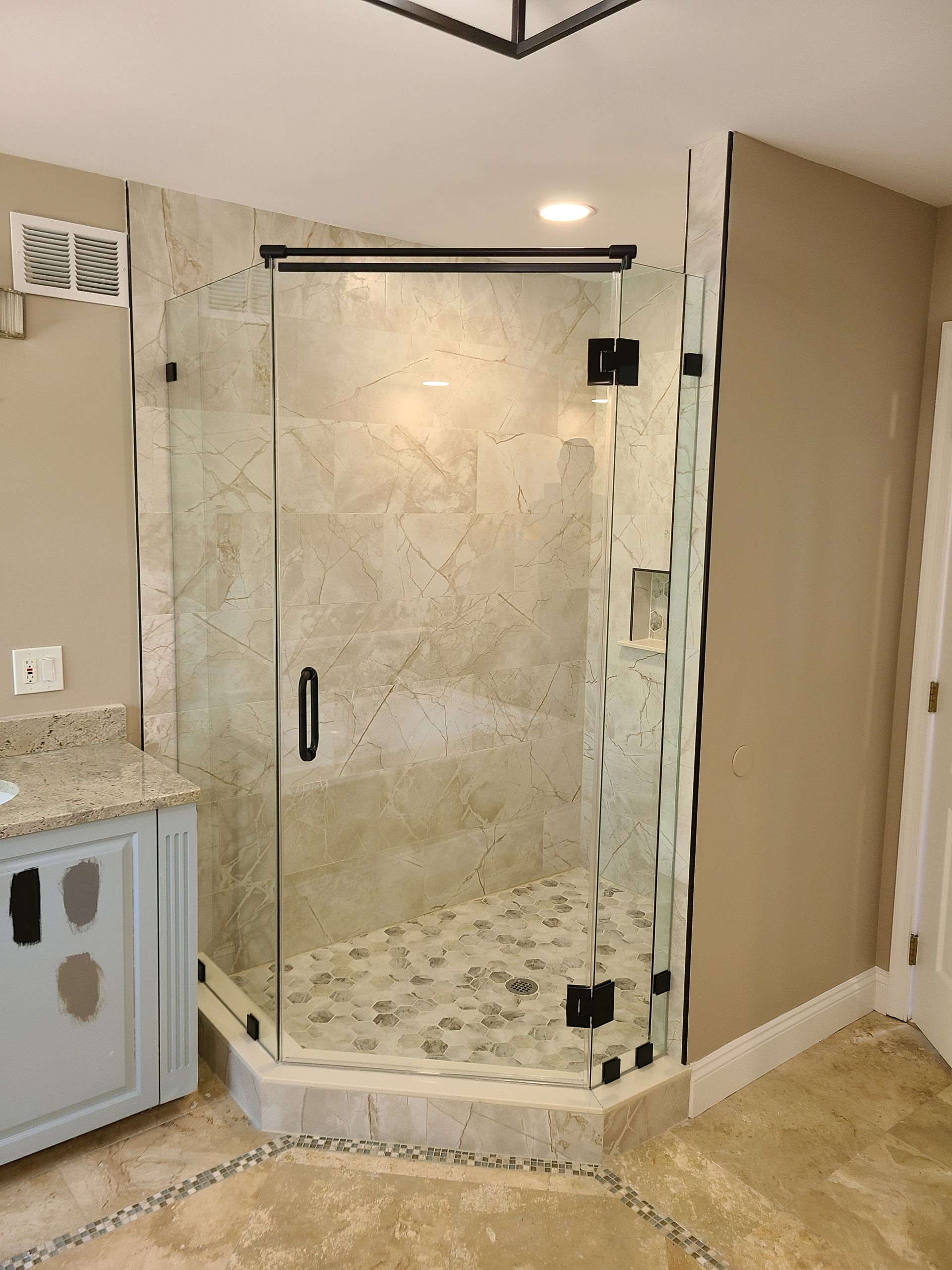 A bathroom with a walk in shower and a sink.