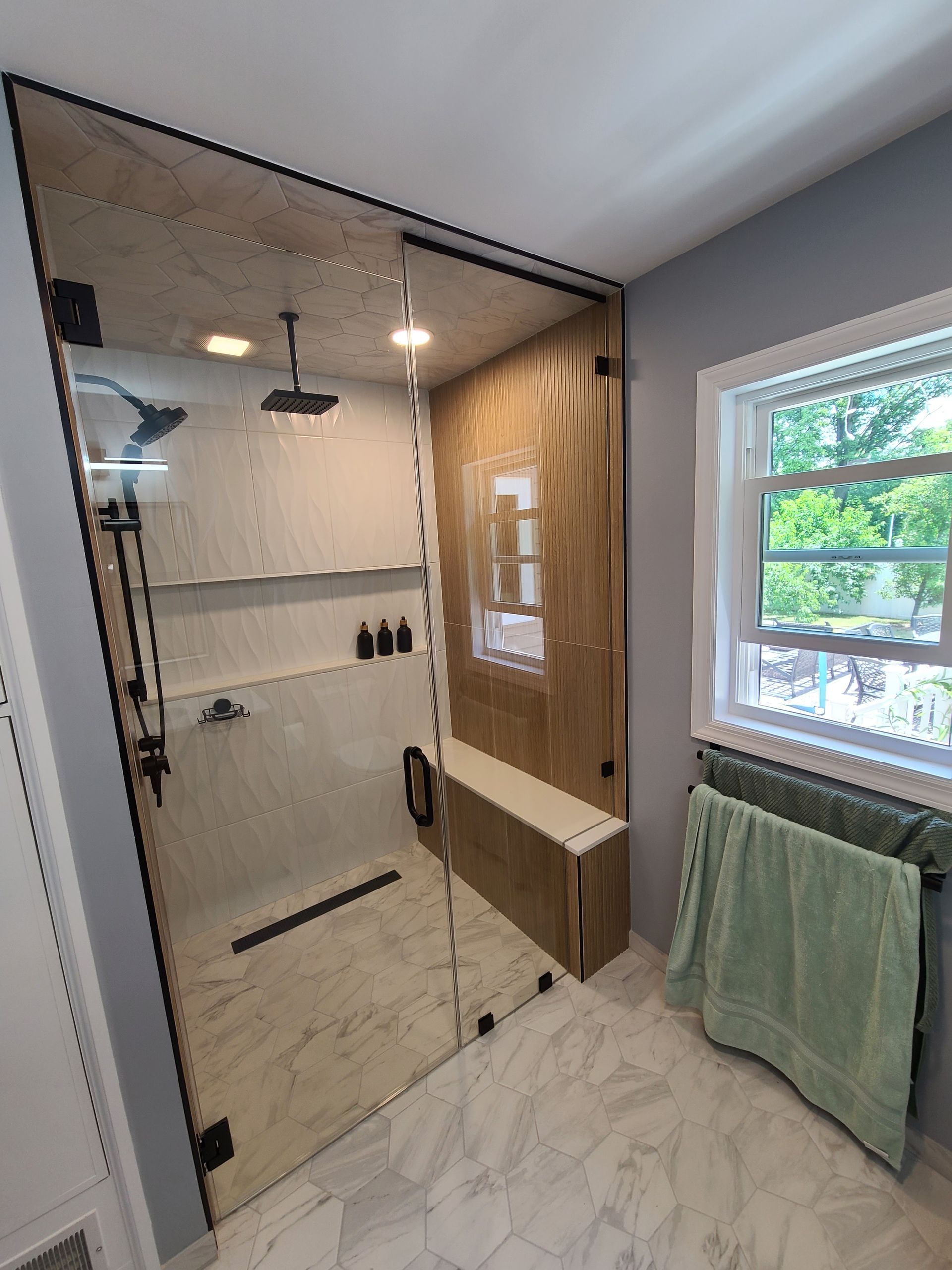 A bathroom with a walk in shower and a window.