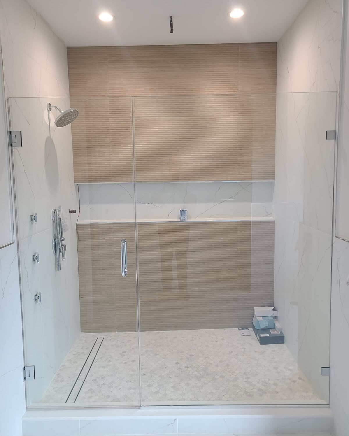 A bathroom with a walk in shower with a glass door