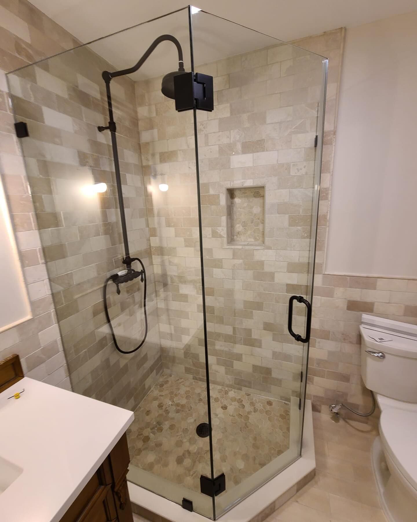 A bathroom with a shower stall , toilet , sink and mirror.