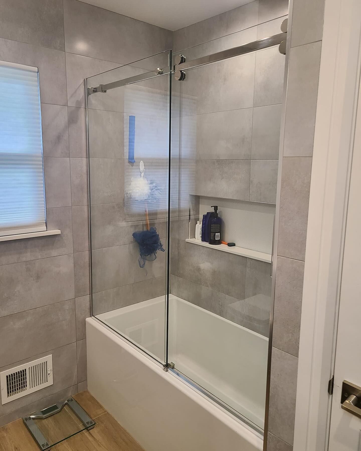A bathroom with a bathtub and a glass shower door.
