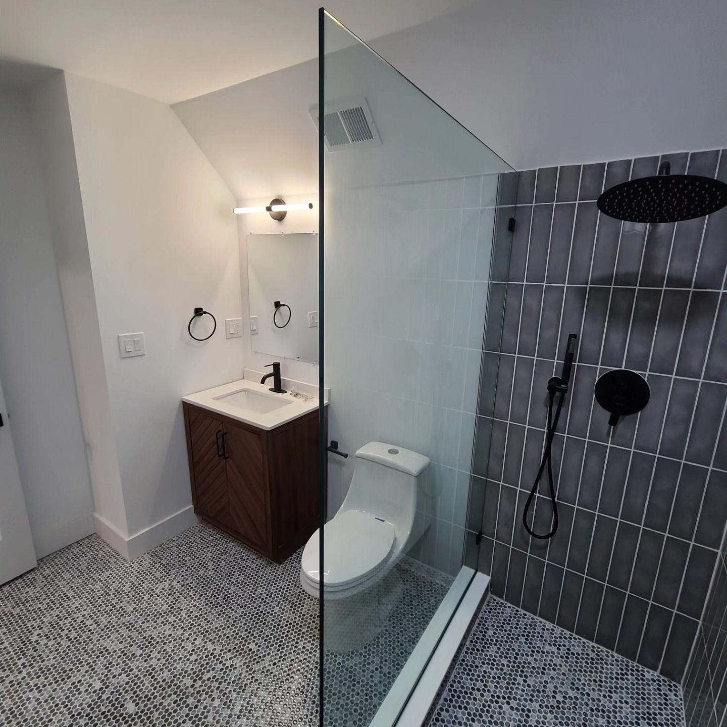 A bathroom with a toilet , sink and shower.