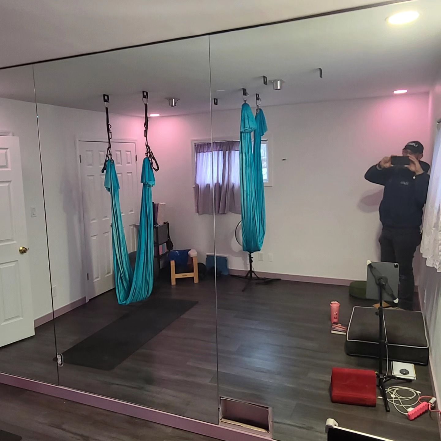A man is standing in front of a large mirror in a room with a hammock hanging from the ceiling.