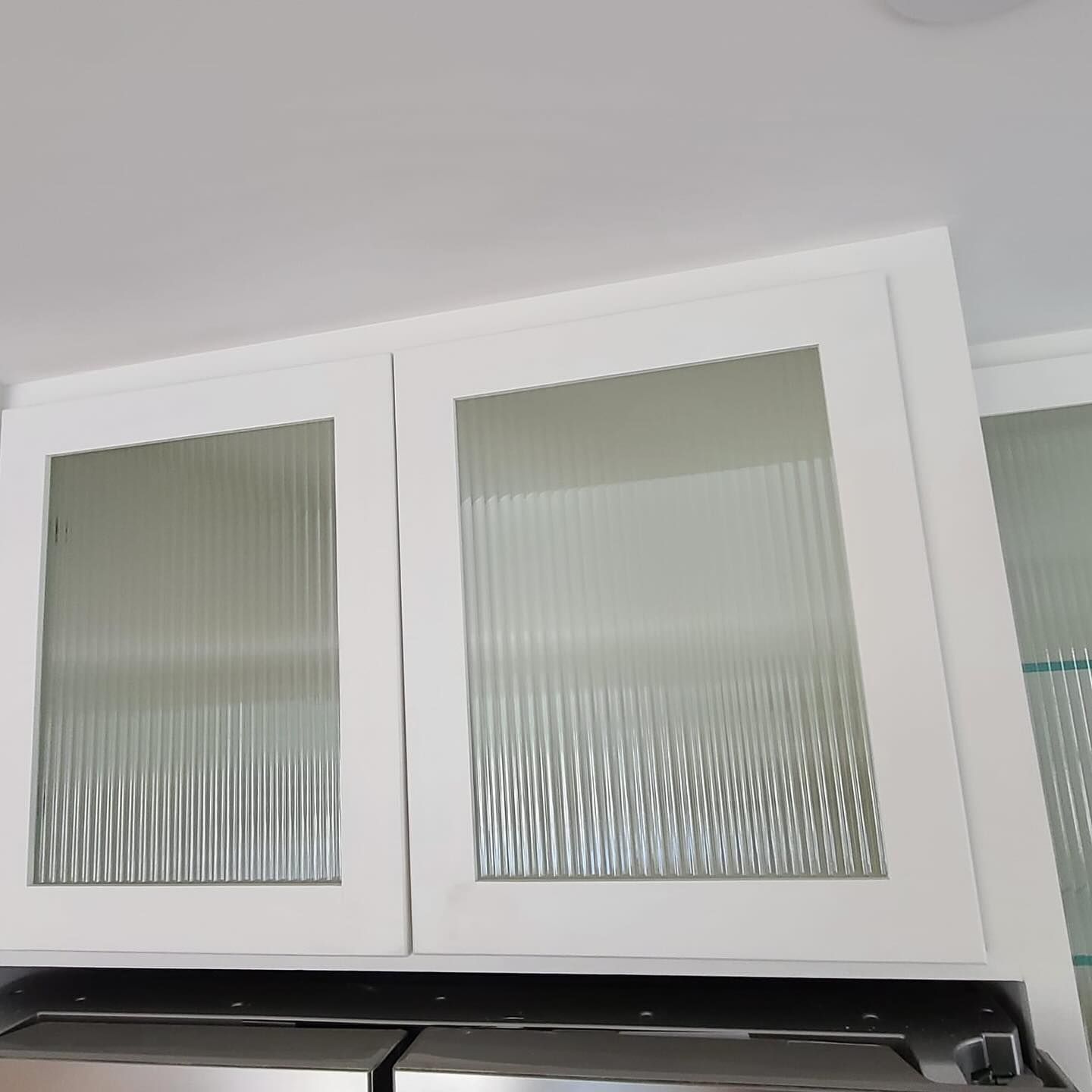 A kitchen with white cabinets and glass doors