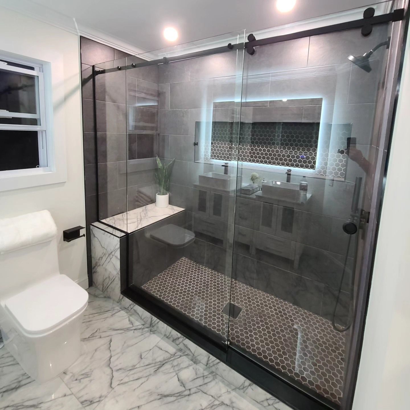 A bathroom with a toilet , sink , shower and mirror.