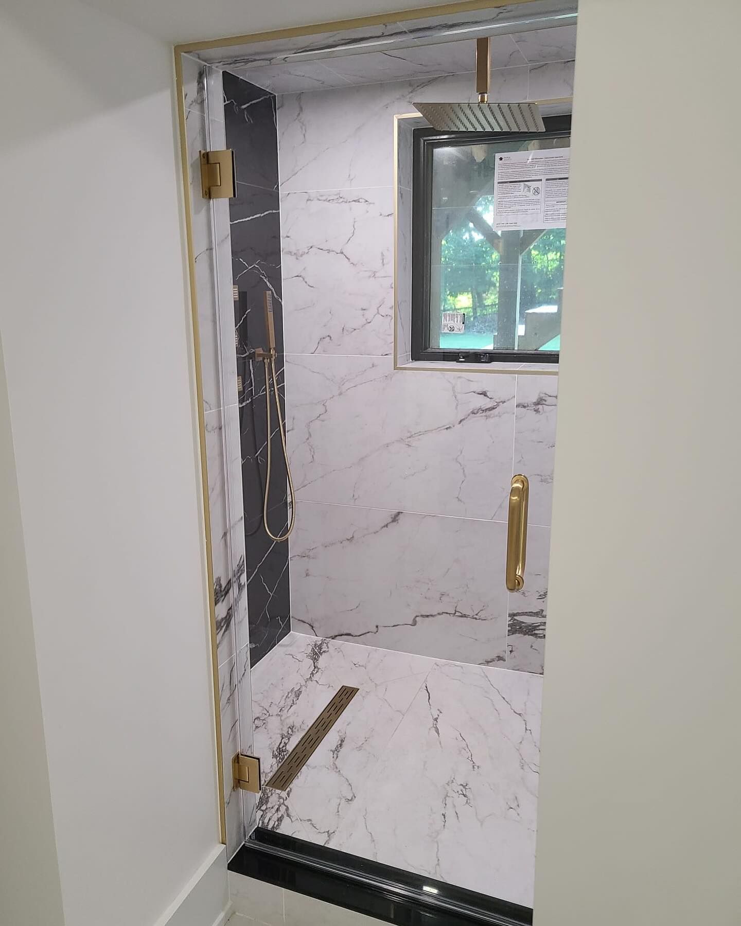 A bathroom with a walk in shower and a window.