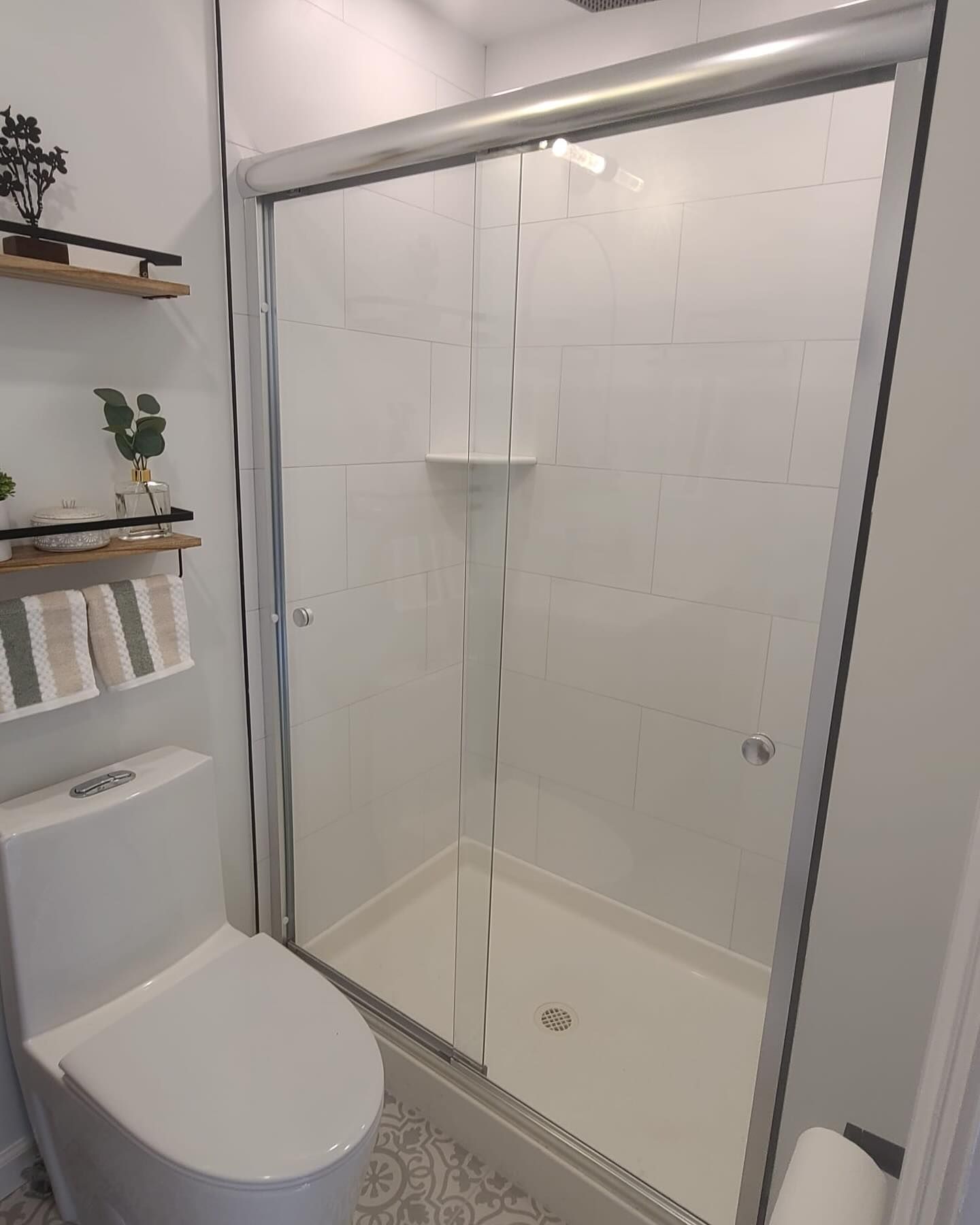 A bathroom with a toilet and a shower with sliding glass doors