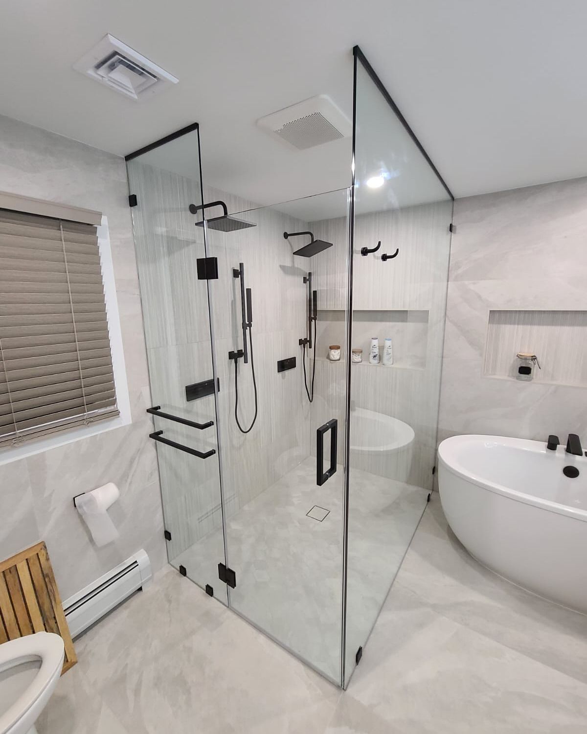 A bathroom with a walk in shower , tub , toilet and window.