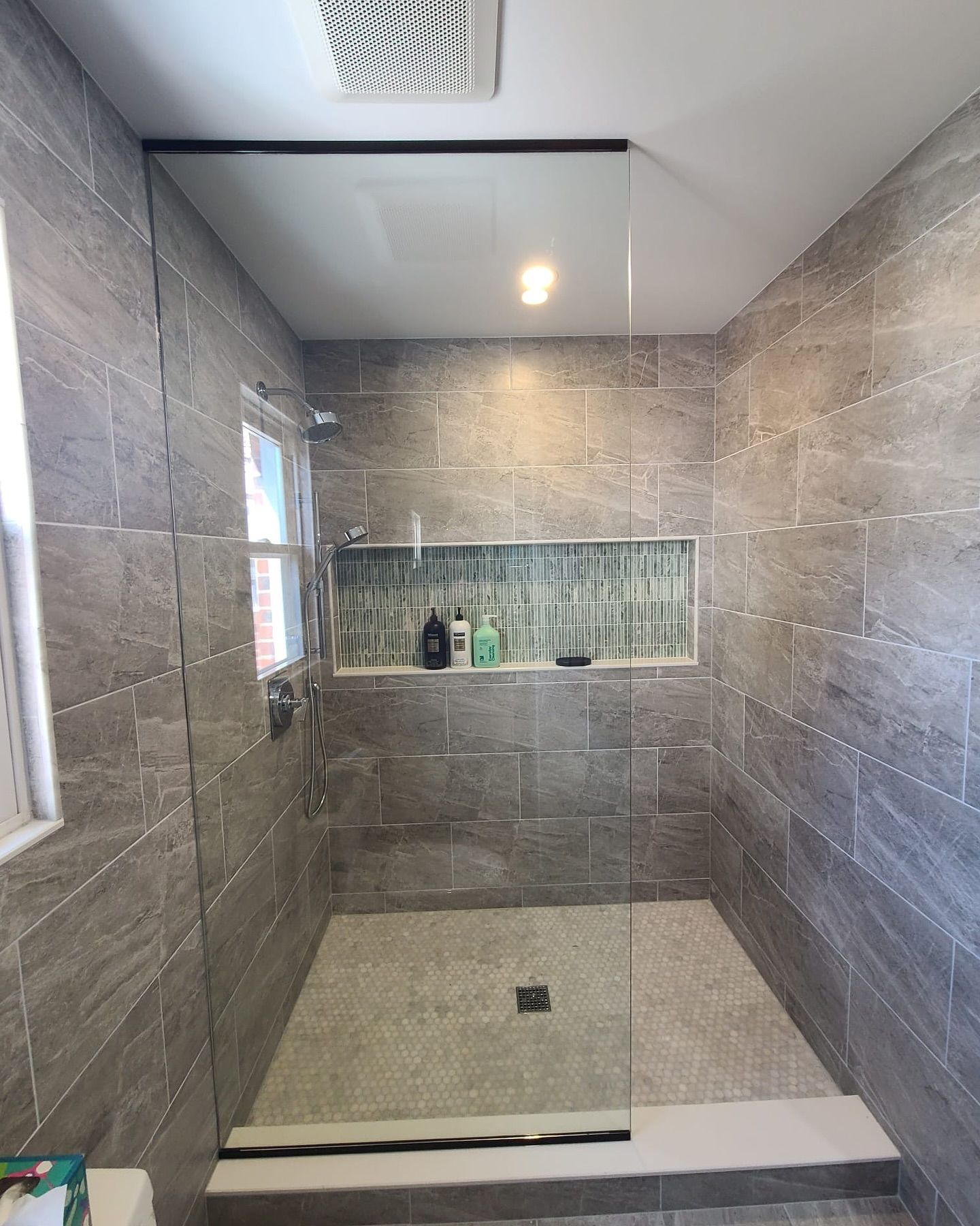 A bathroom with a walk in shower and a window.