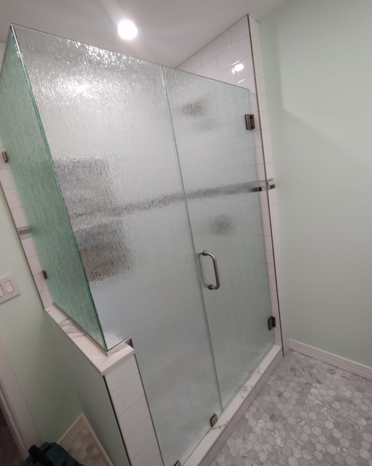 A bathroom with a shower stall with a frosted glass door.