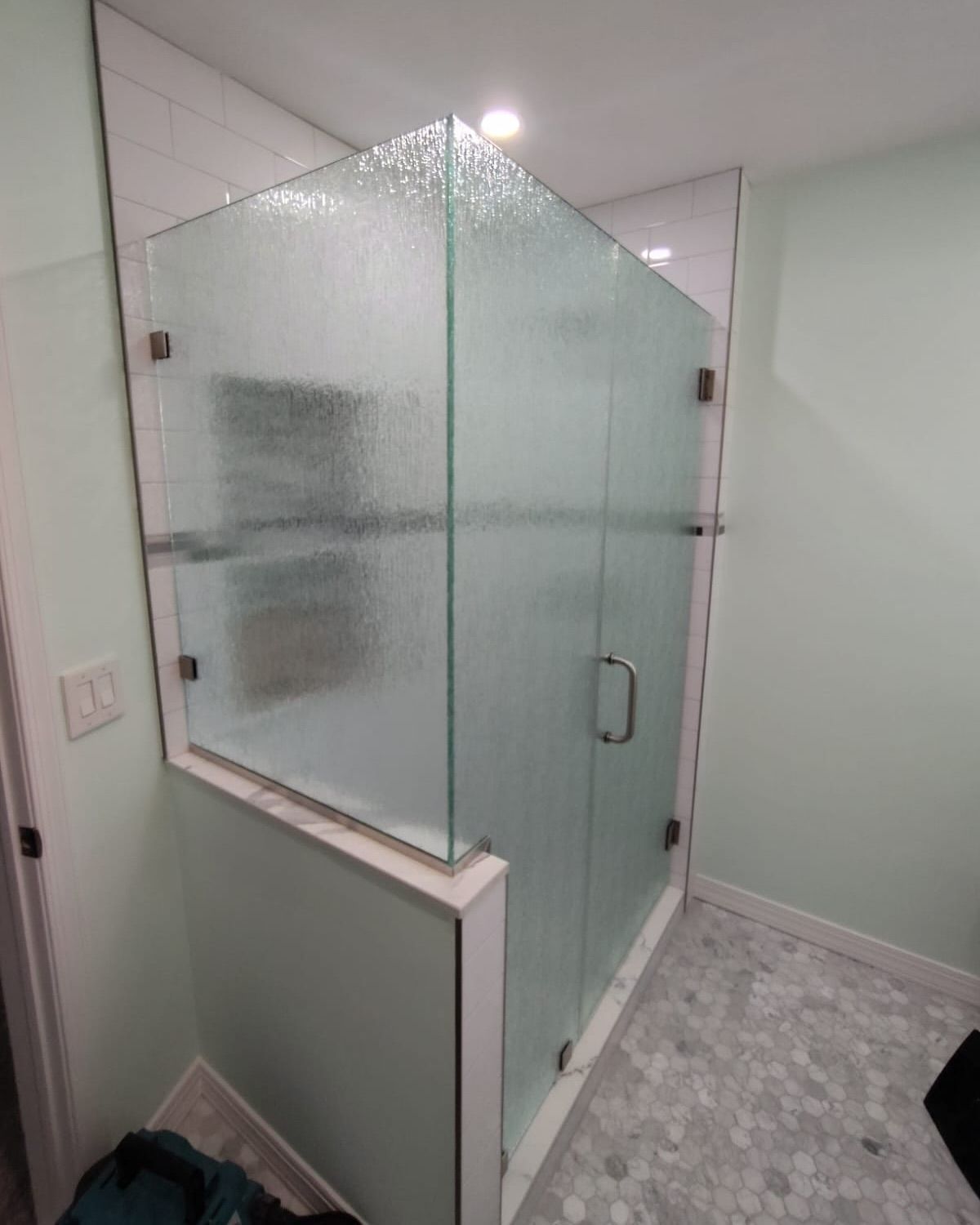 A bathroom with a glass shower door and a mirror.