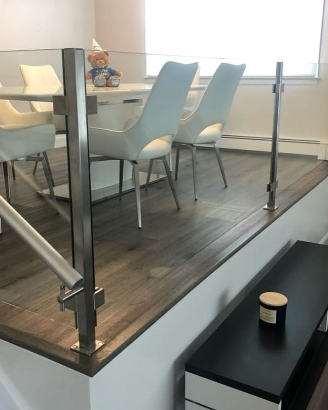 A dining room with a table and chairs and a glass railing