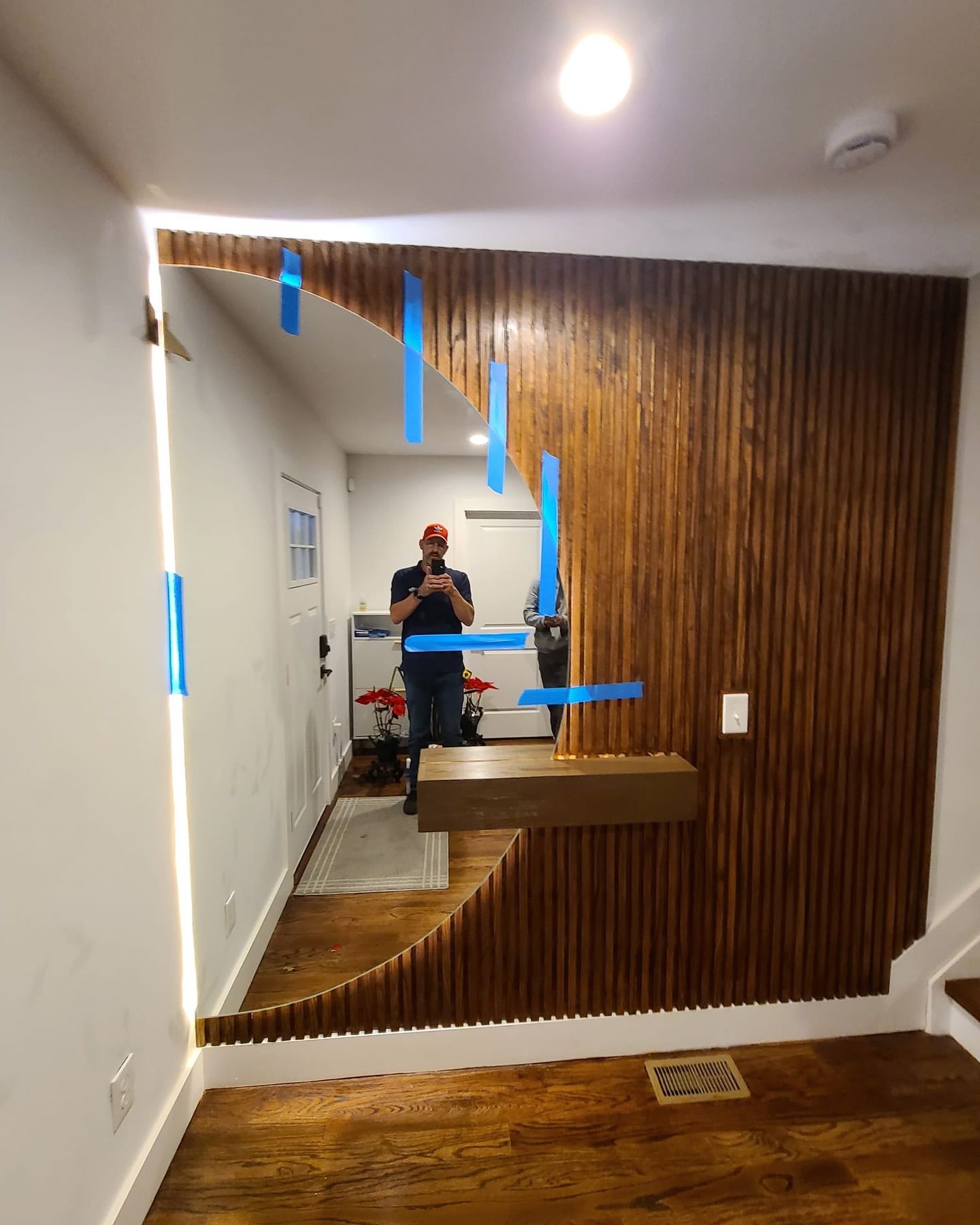 A man is standing in front of a large mirror in a hallway