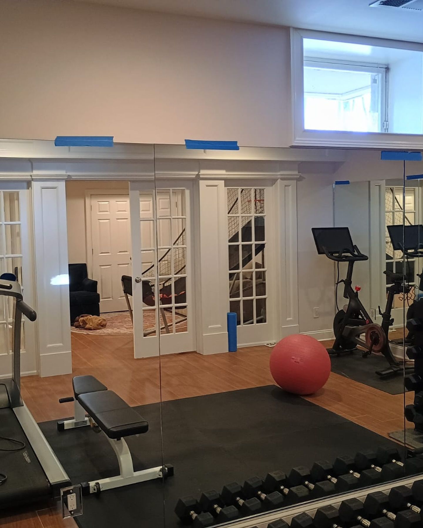 A gym with a treadmill , exercise ball , and dumbbells.