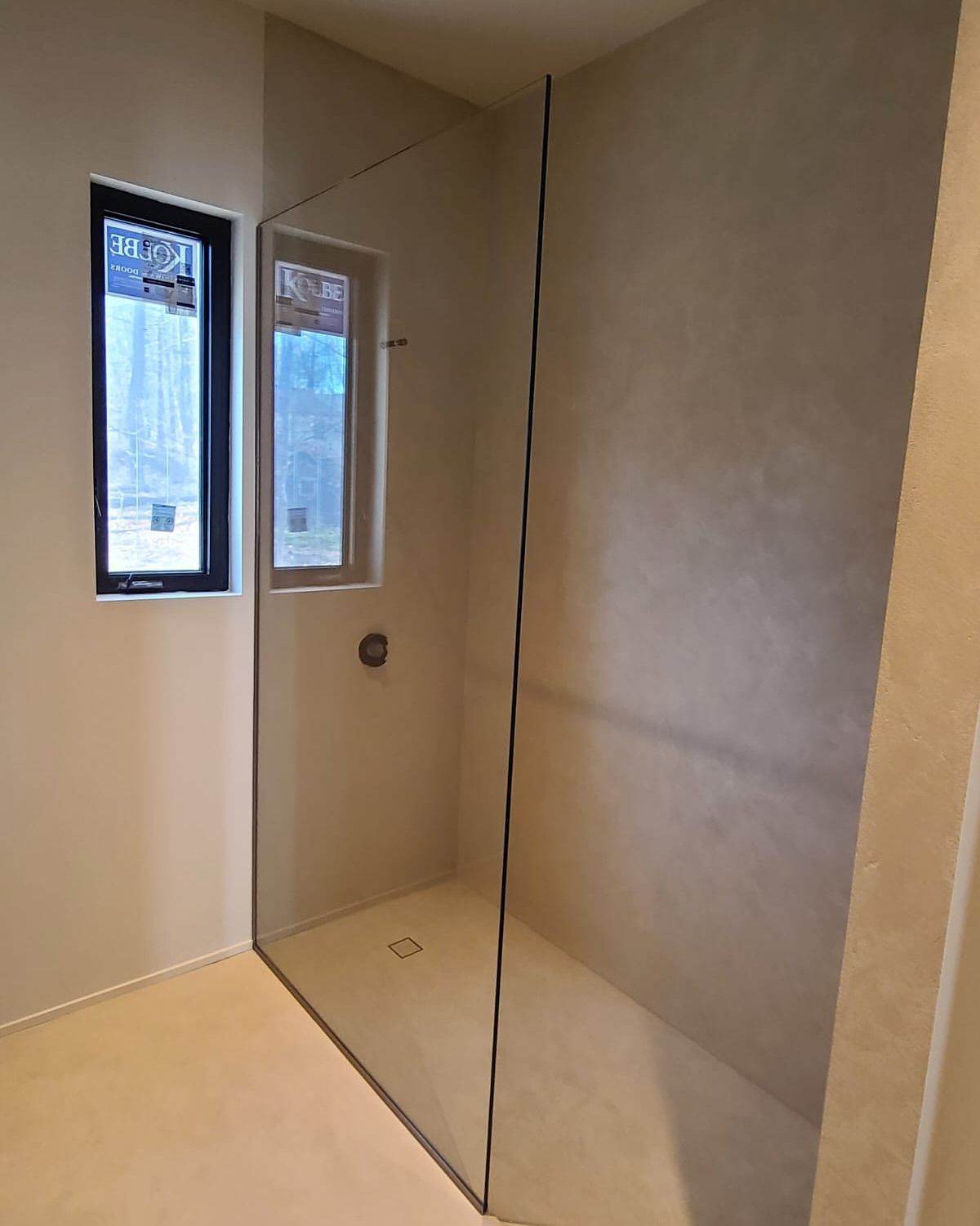 A bathroom with a walk in shower and a window.