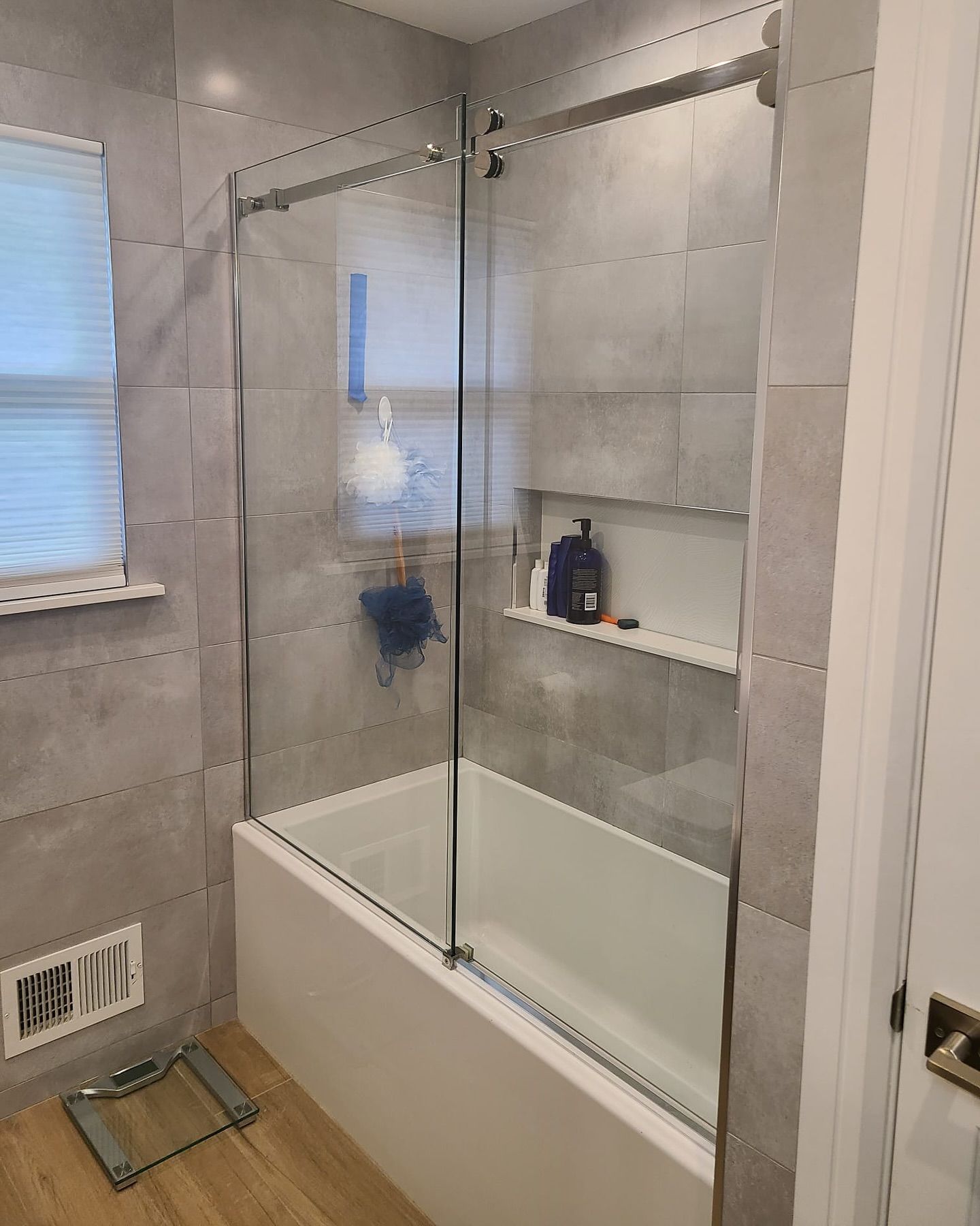 A bathroom with a bathtub and a glass shower door.