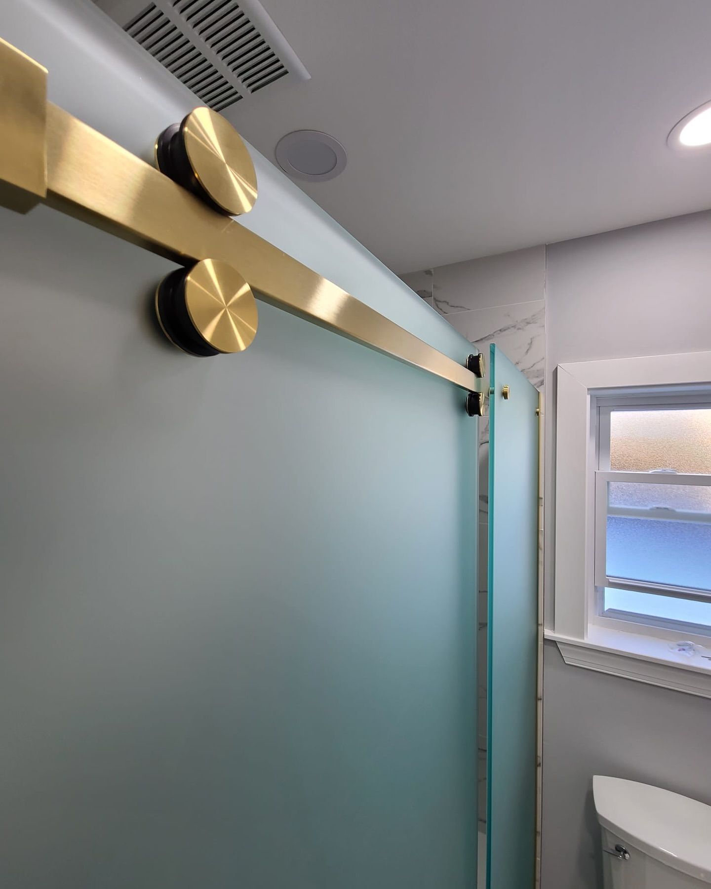 A bathroom with a sliding glass door and a toilet