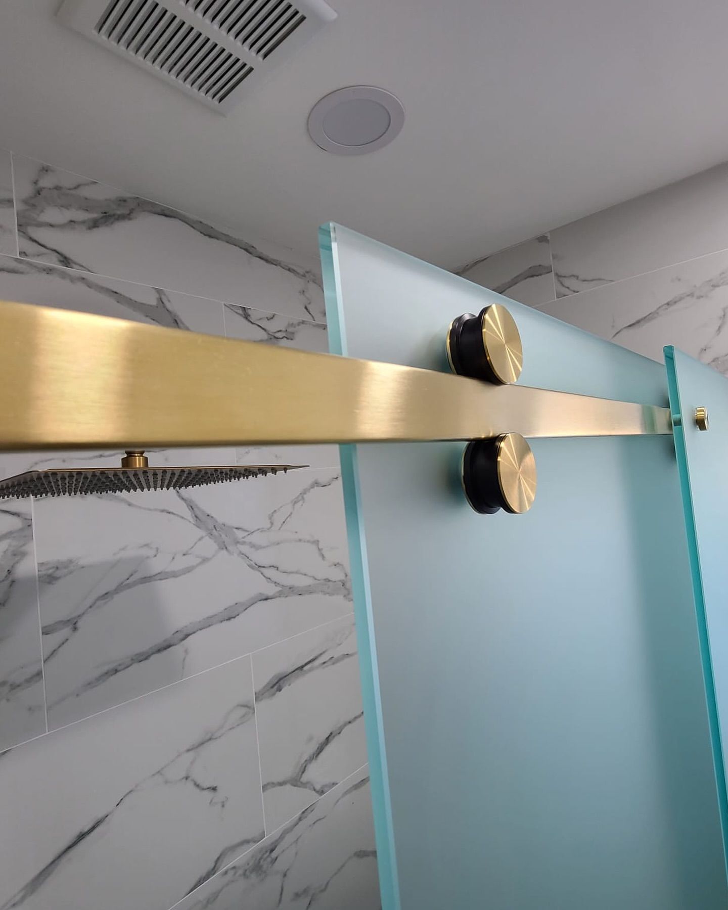 A bathroom with a sliding glass door and a brass railing.