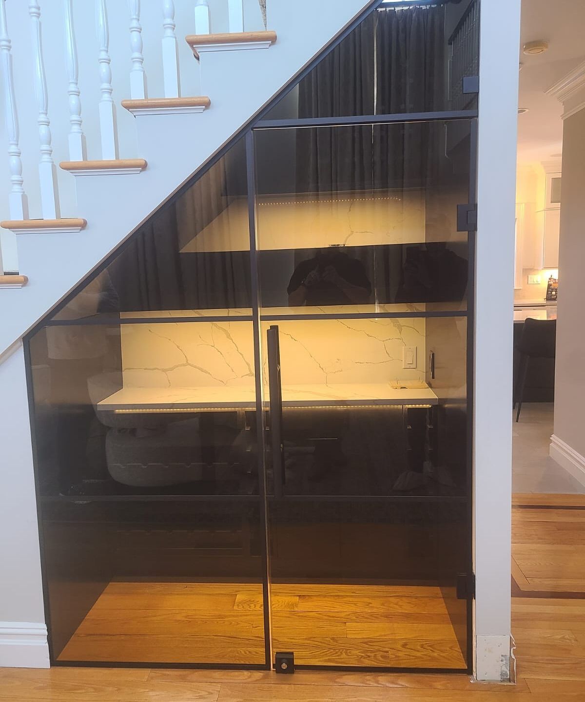 A kitchen under a staircase with a glass door.